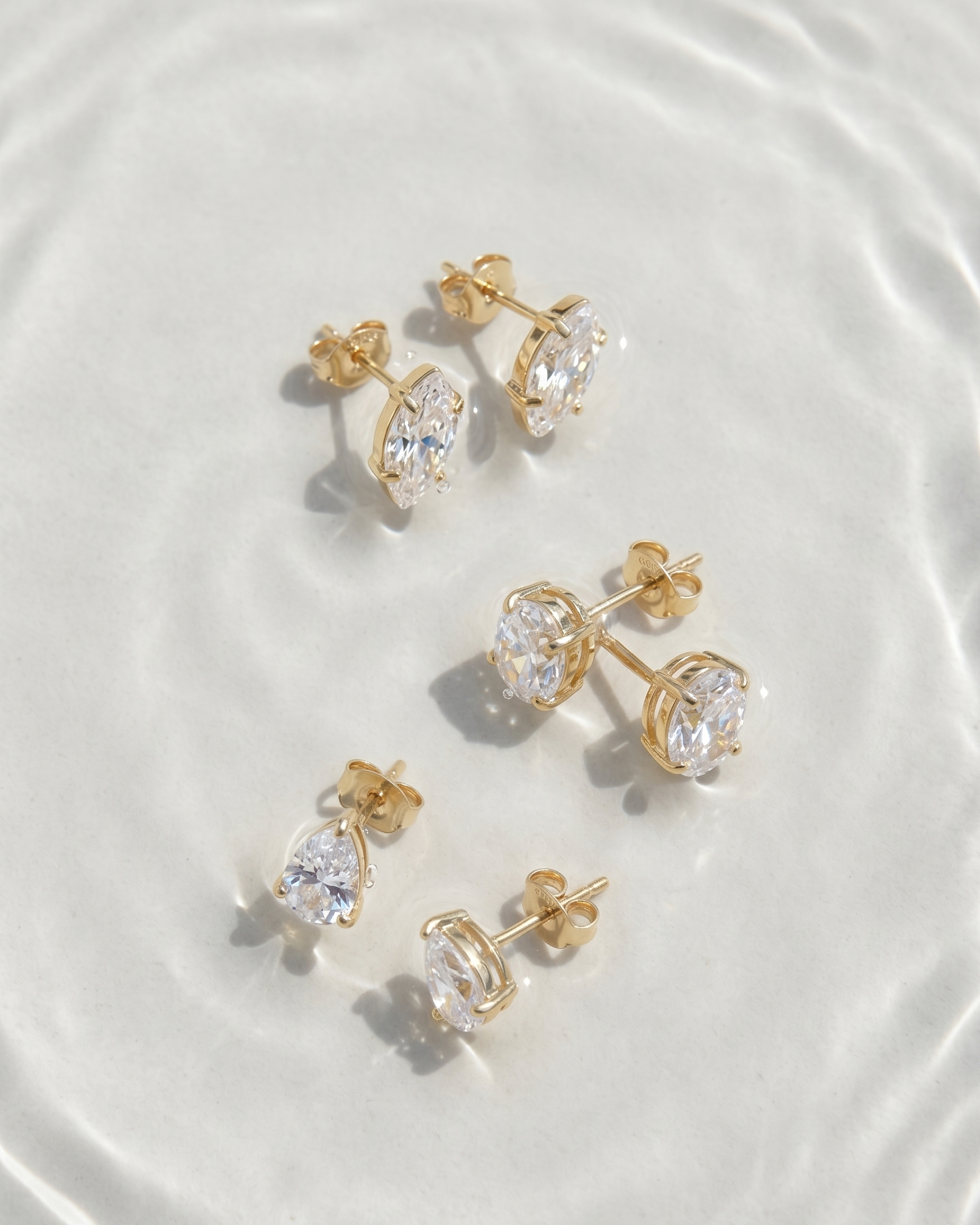 Gold and clear crystal stud earrings on a white plate