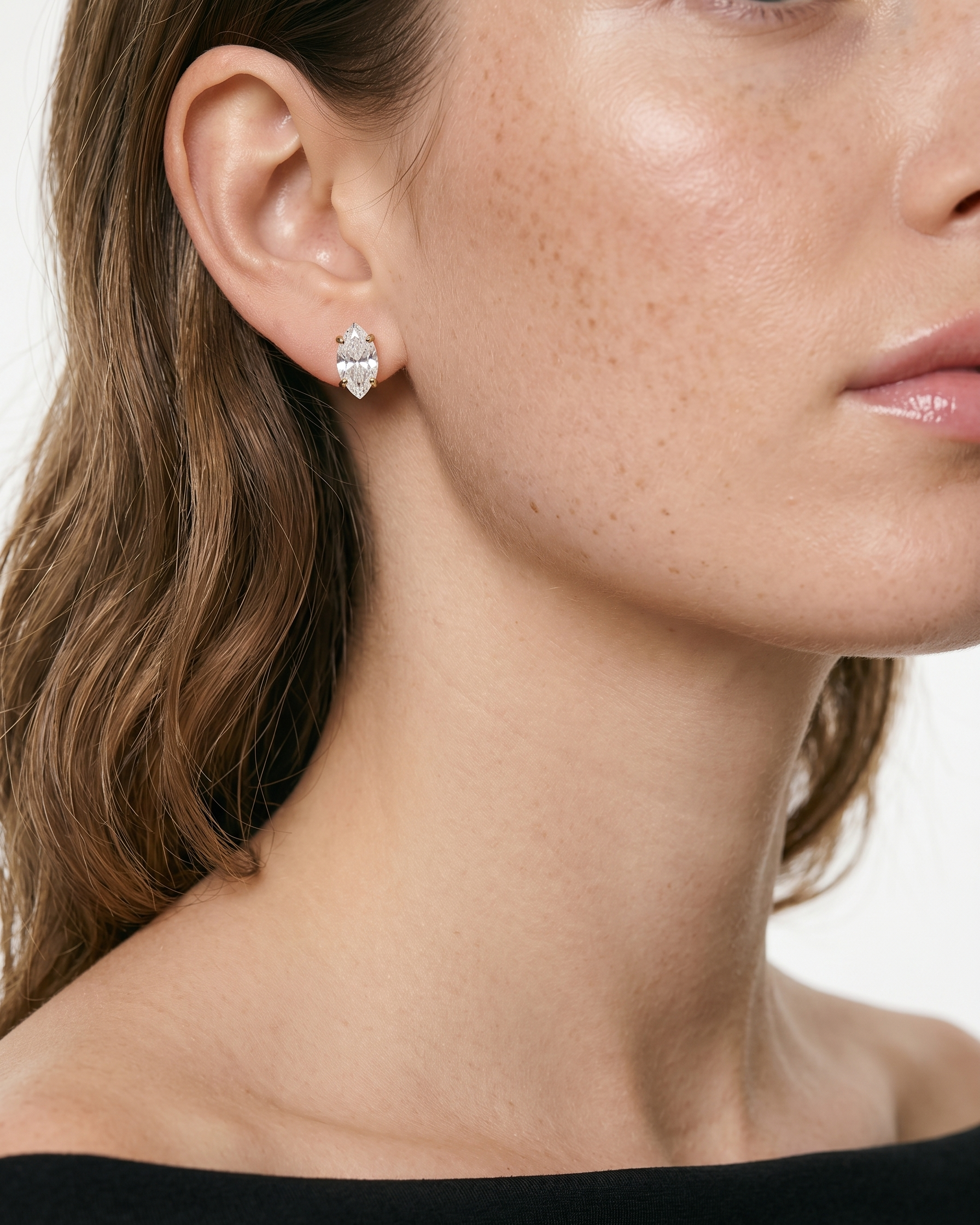 Close-up of a woman wearing a diamond earring with a neutral background