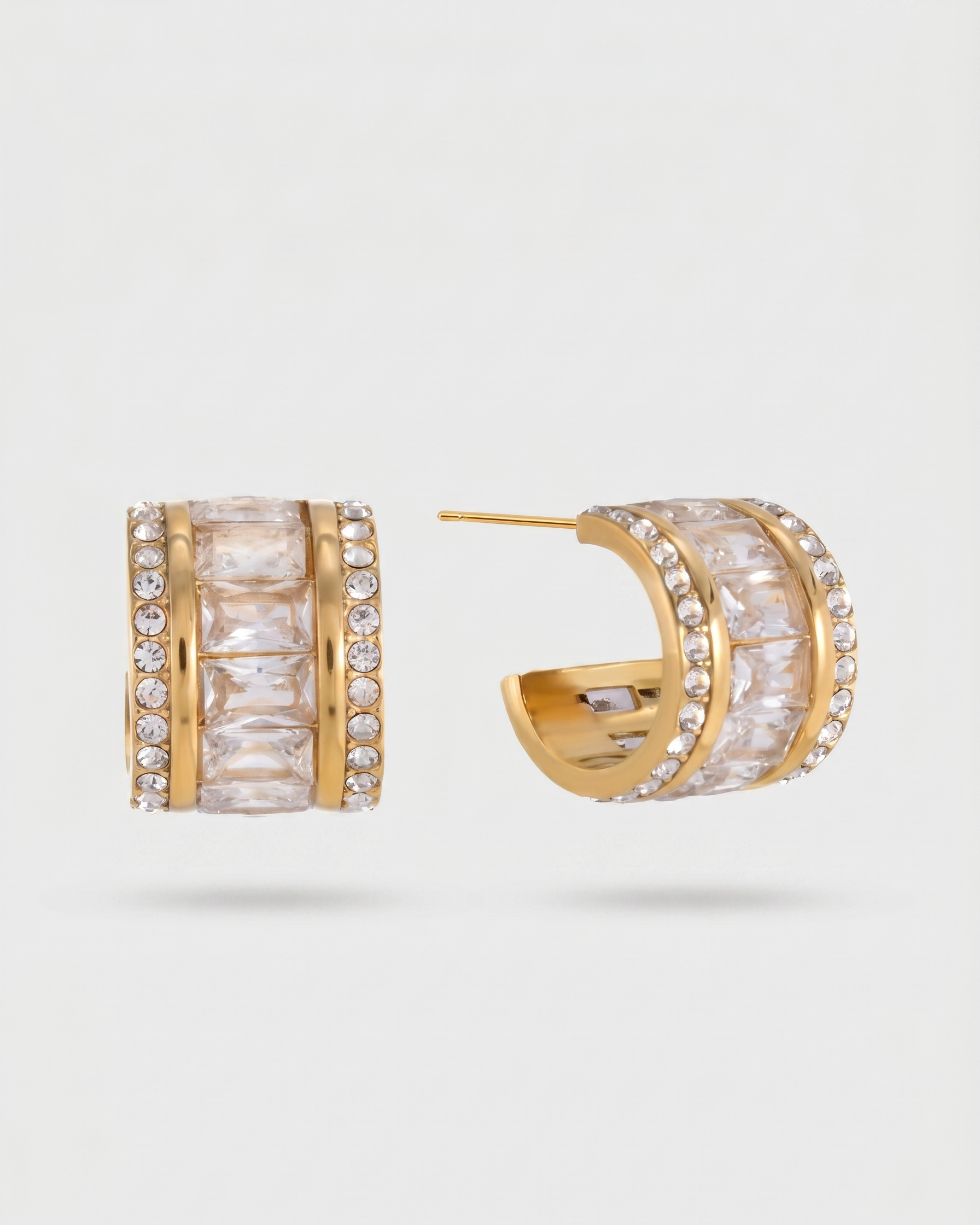 Gold hoop earrings with clear gemstones on a light gray background