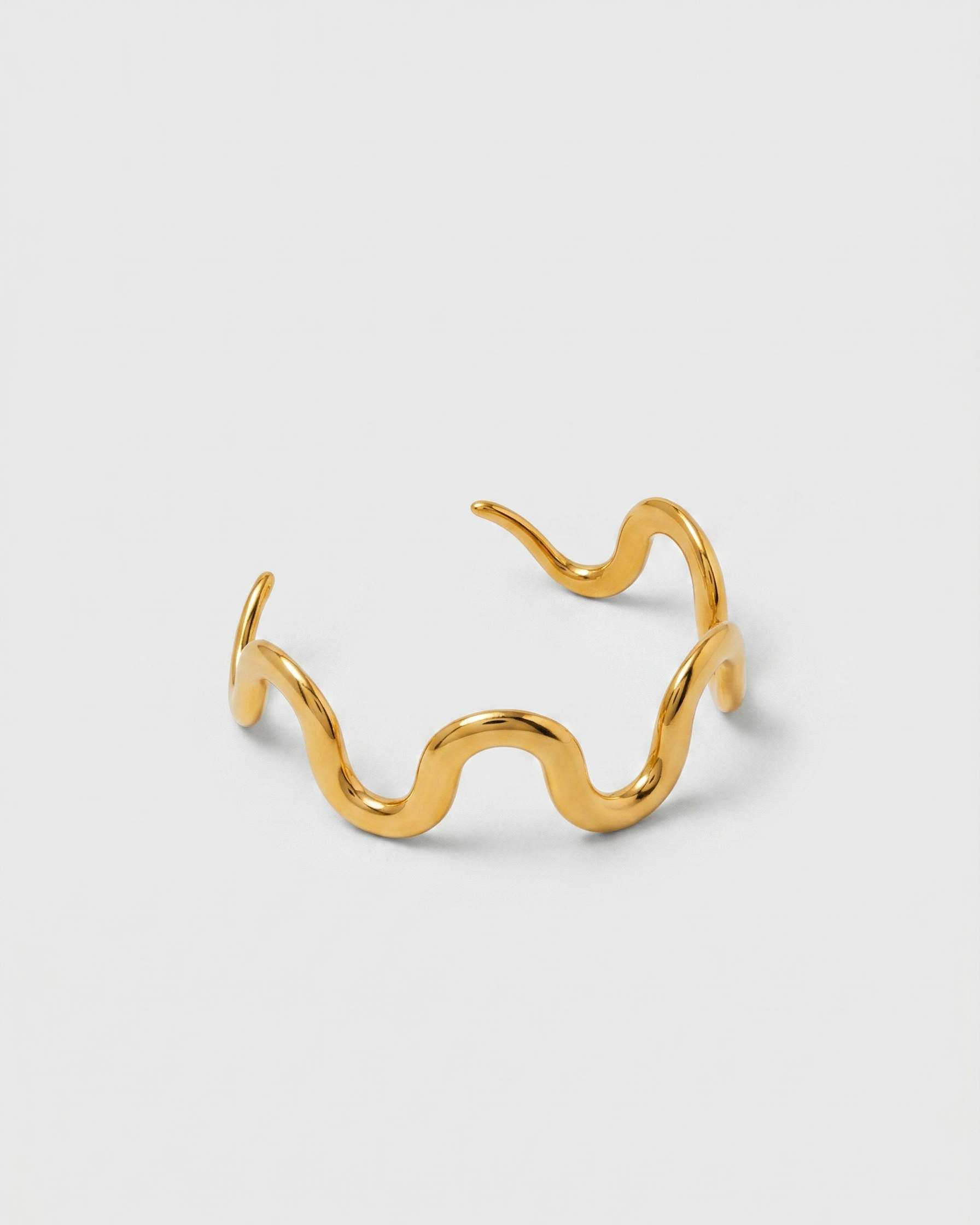 Gold open-wire cuff on a light gray background