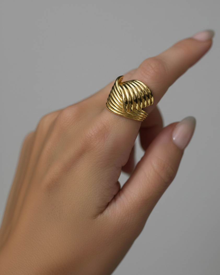 Gold ring on a finger against a neutral background