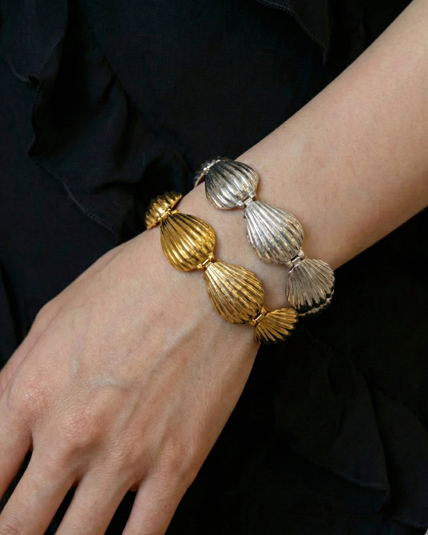 Gold and silver bracelet on a wrist against a black background