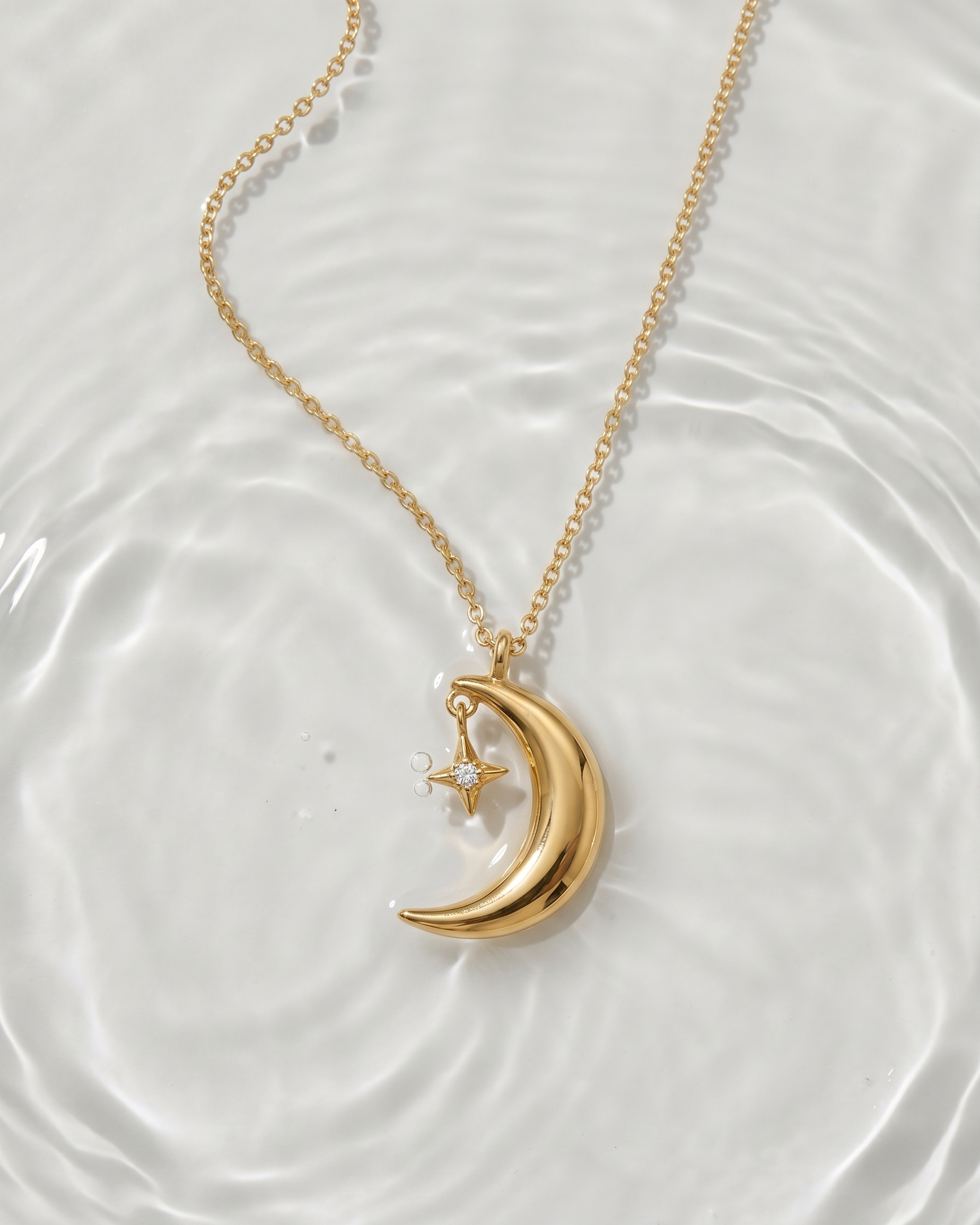 Gold necklace with a crescent moon and star pendant on a white background