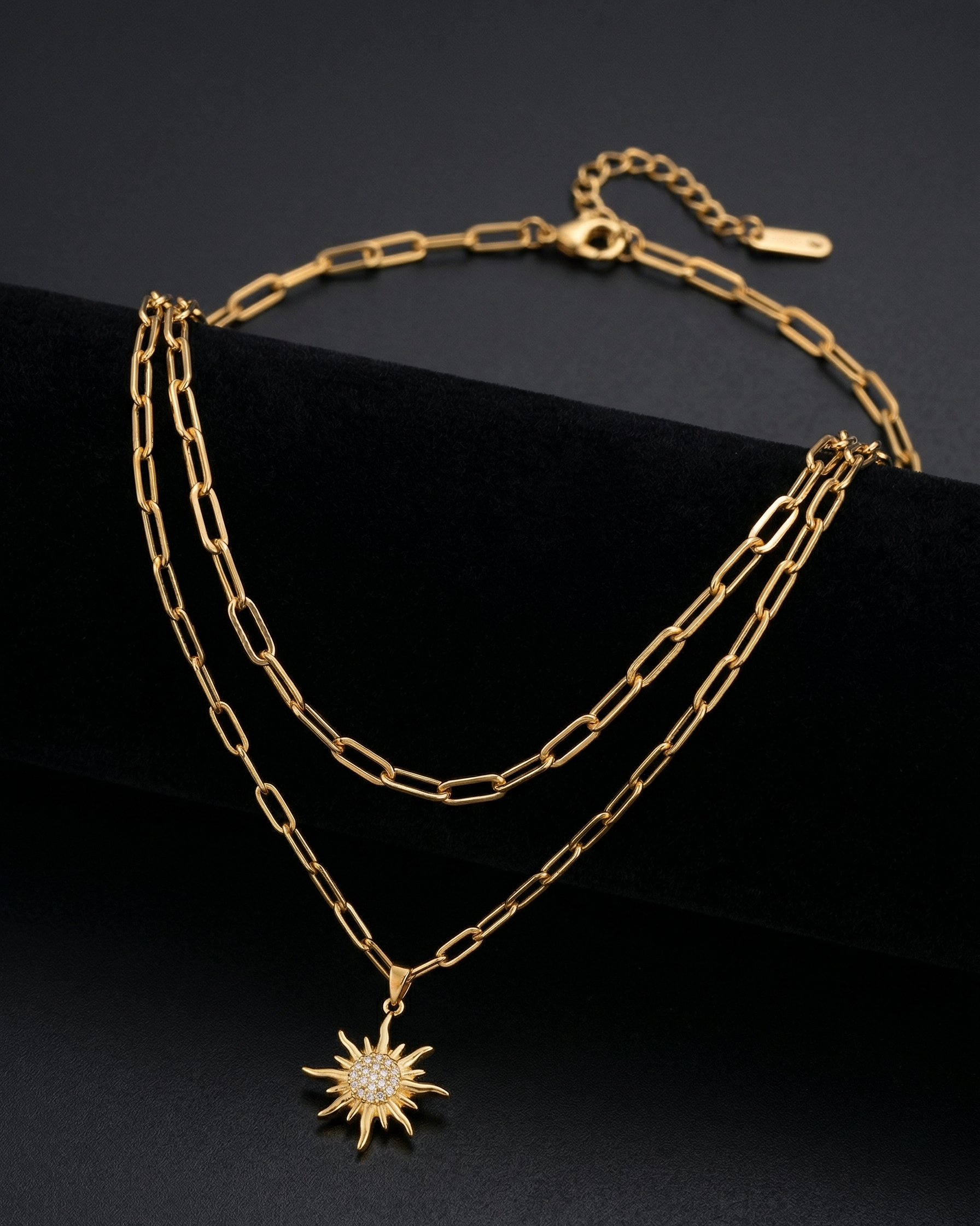 Gold chain necklace with a sun pendant on a black background