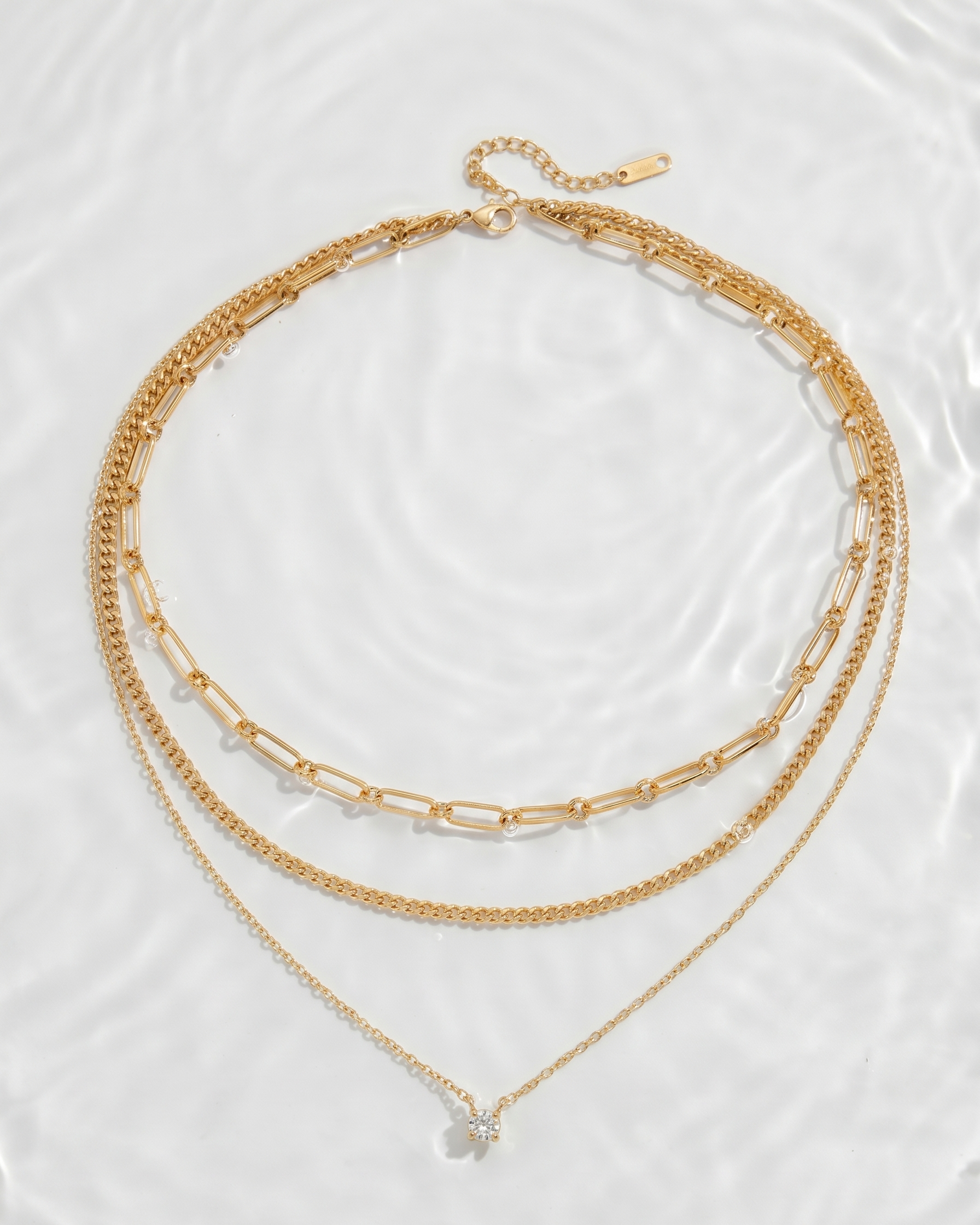 Two gold necklaces on a clear glass surface