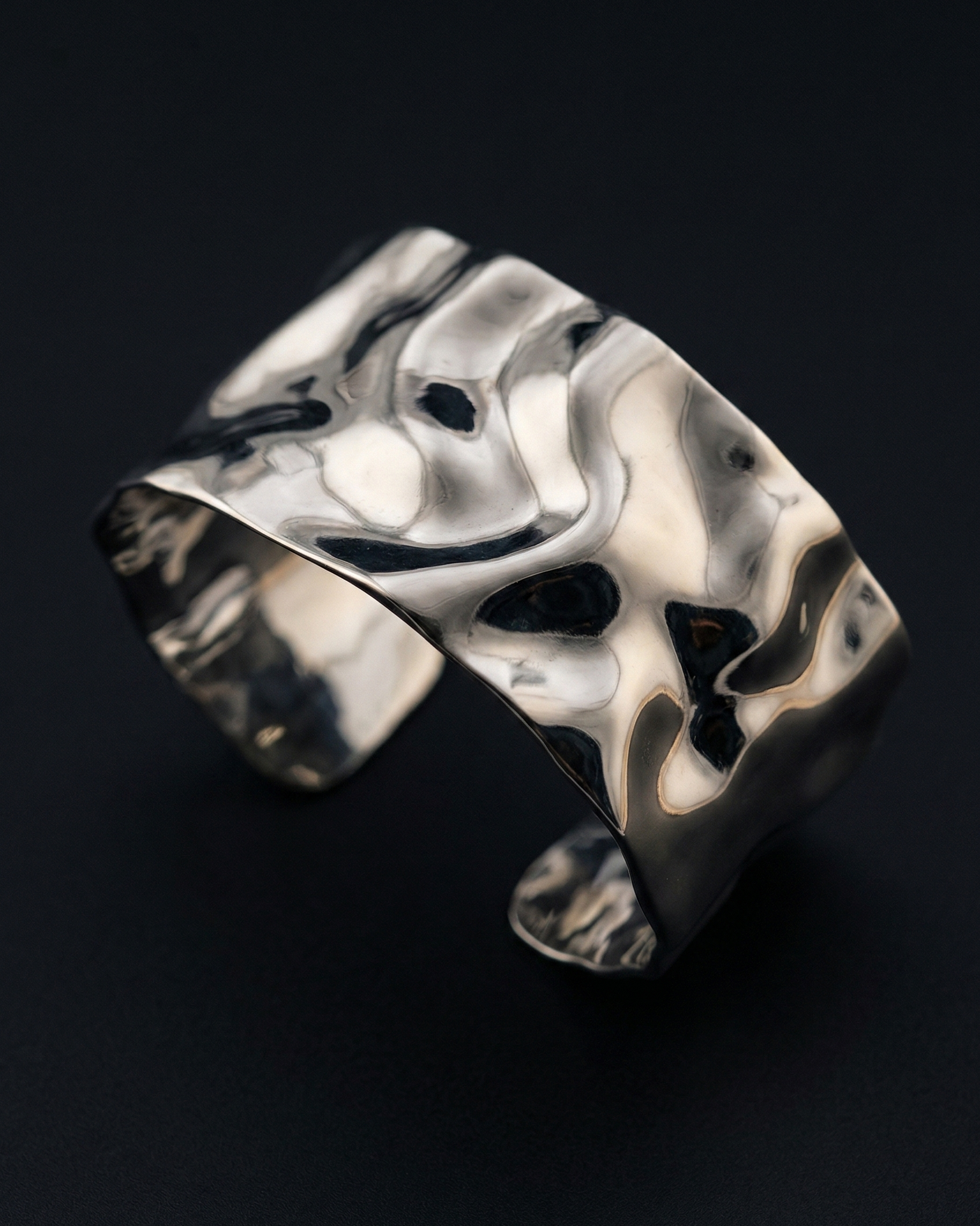 Silver ring with a unique, organic design on a black background