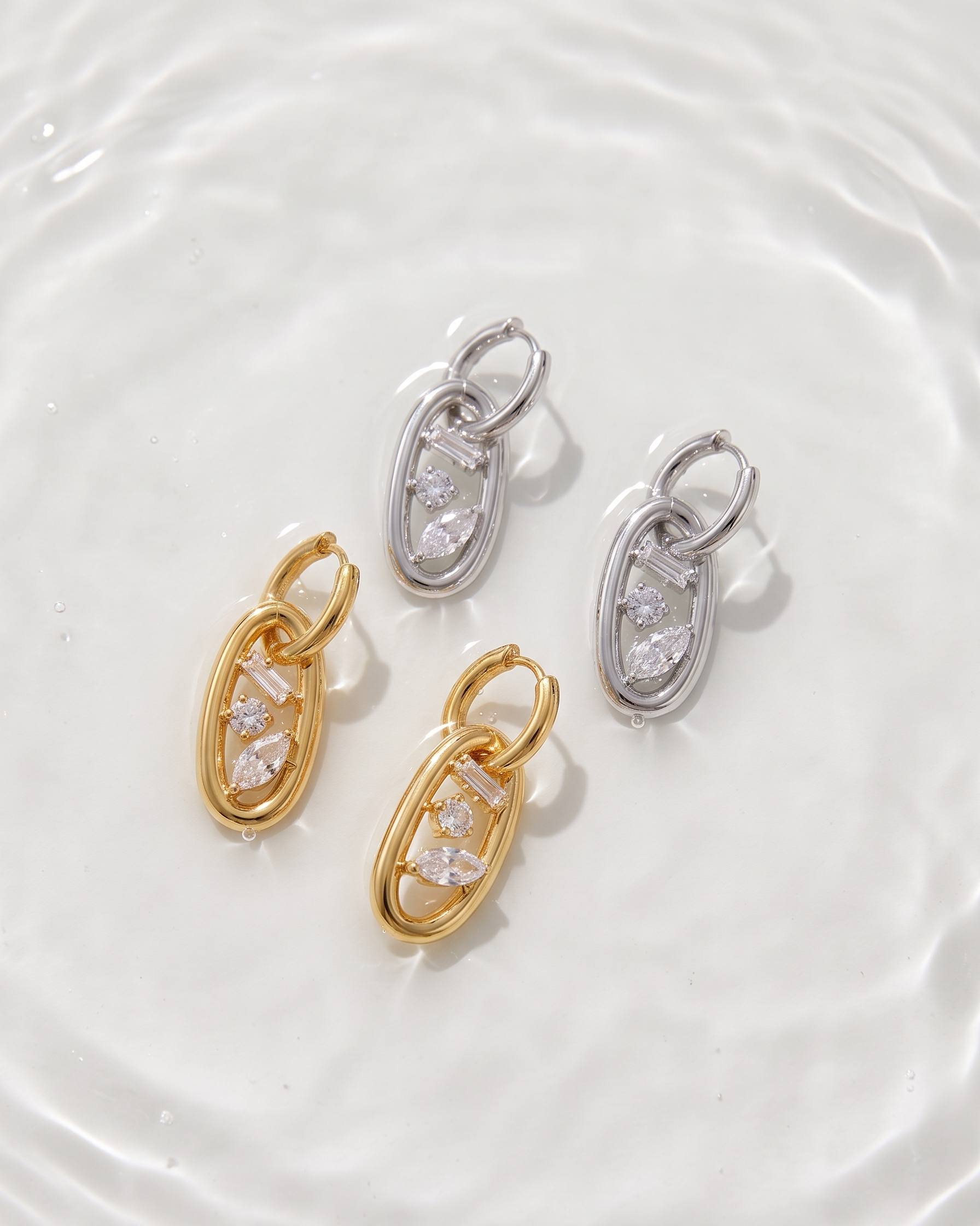 Two pairs of gold and silver earrings on a white plate