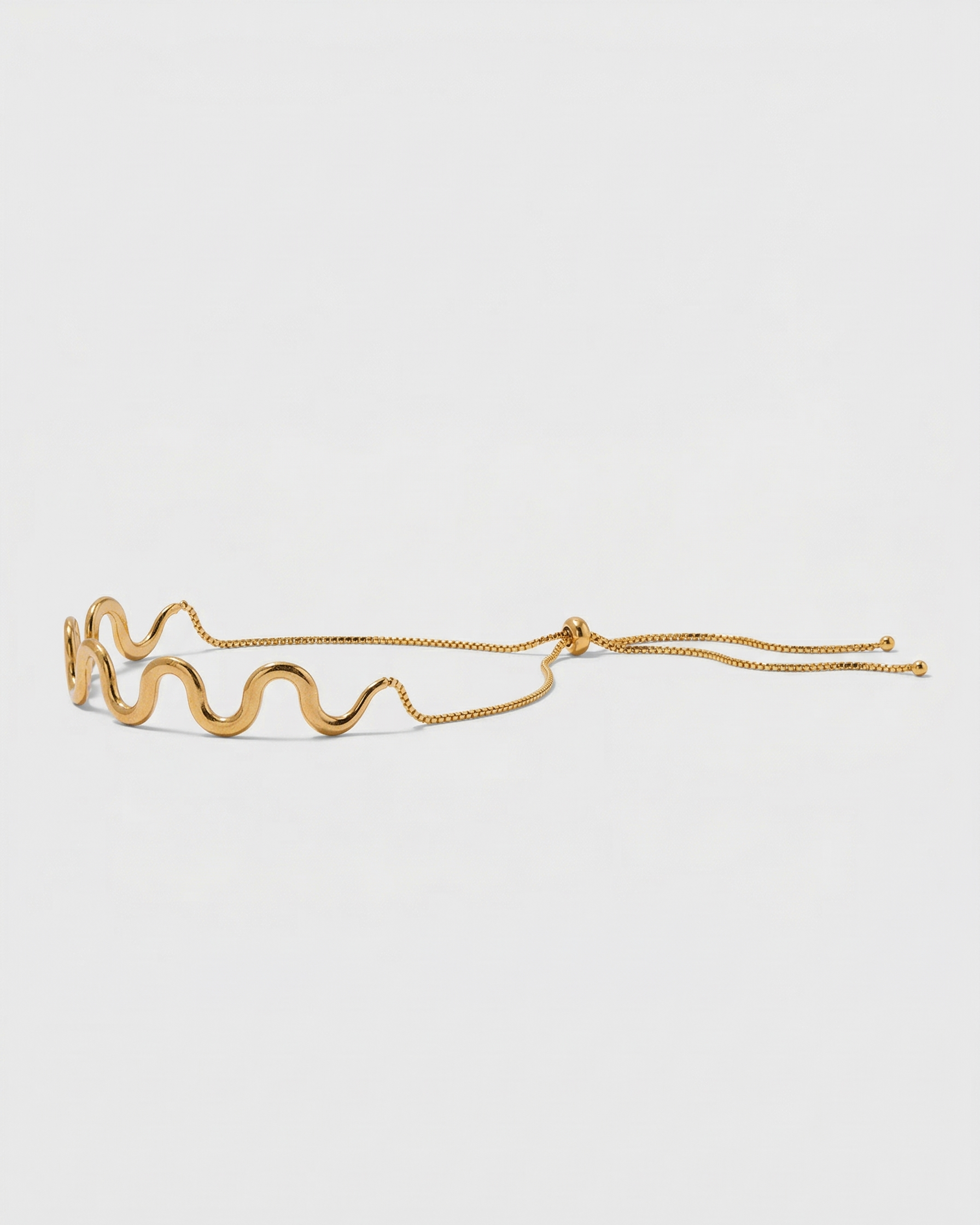 Gold bracelet with a wavy design on a white background