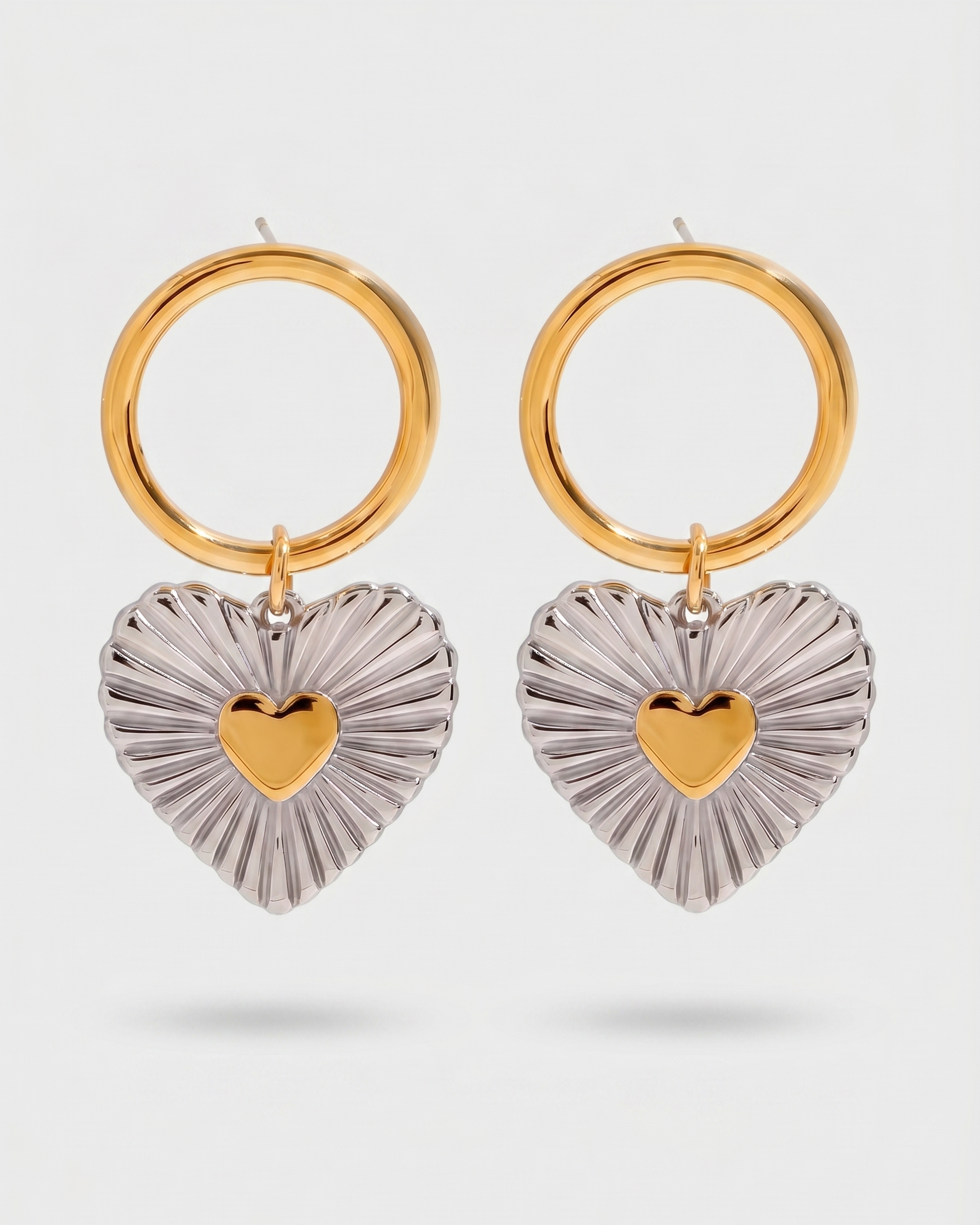 Gold and silver heart-shaped earrings on a white background