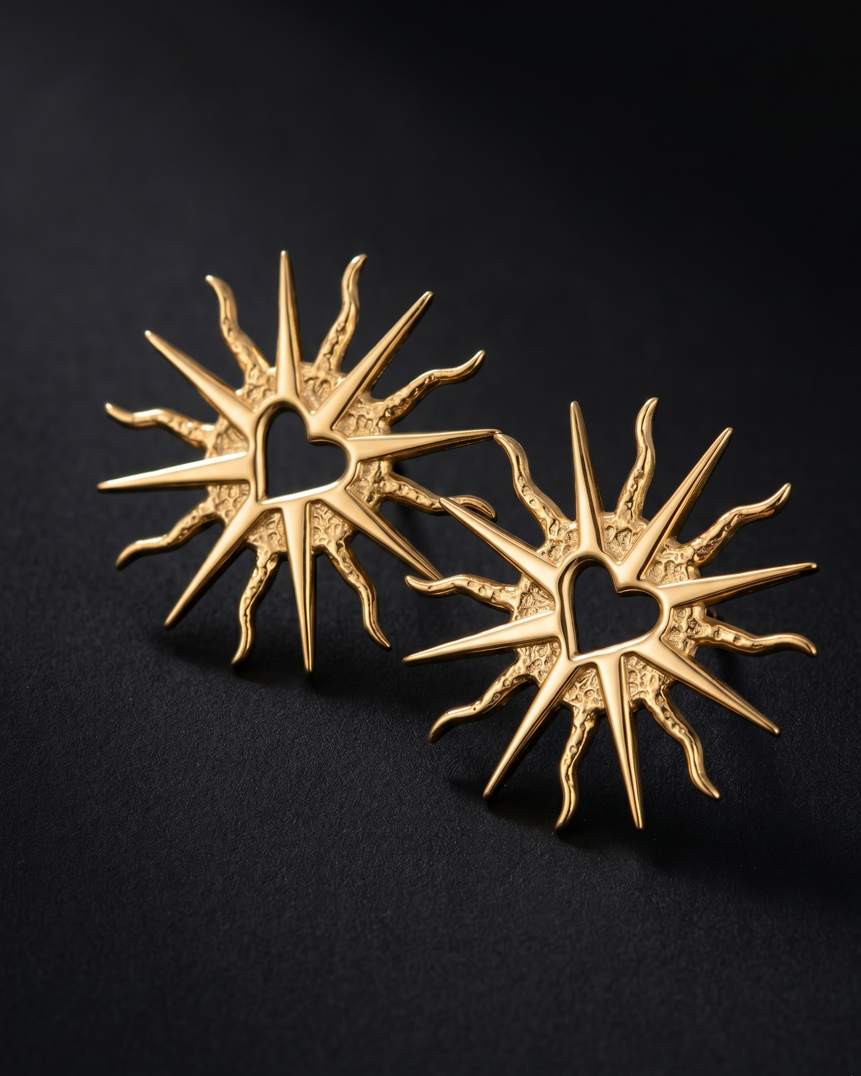 Pair of gold sun-shaped earrings on a black background