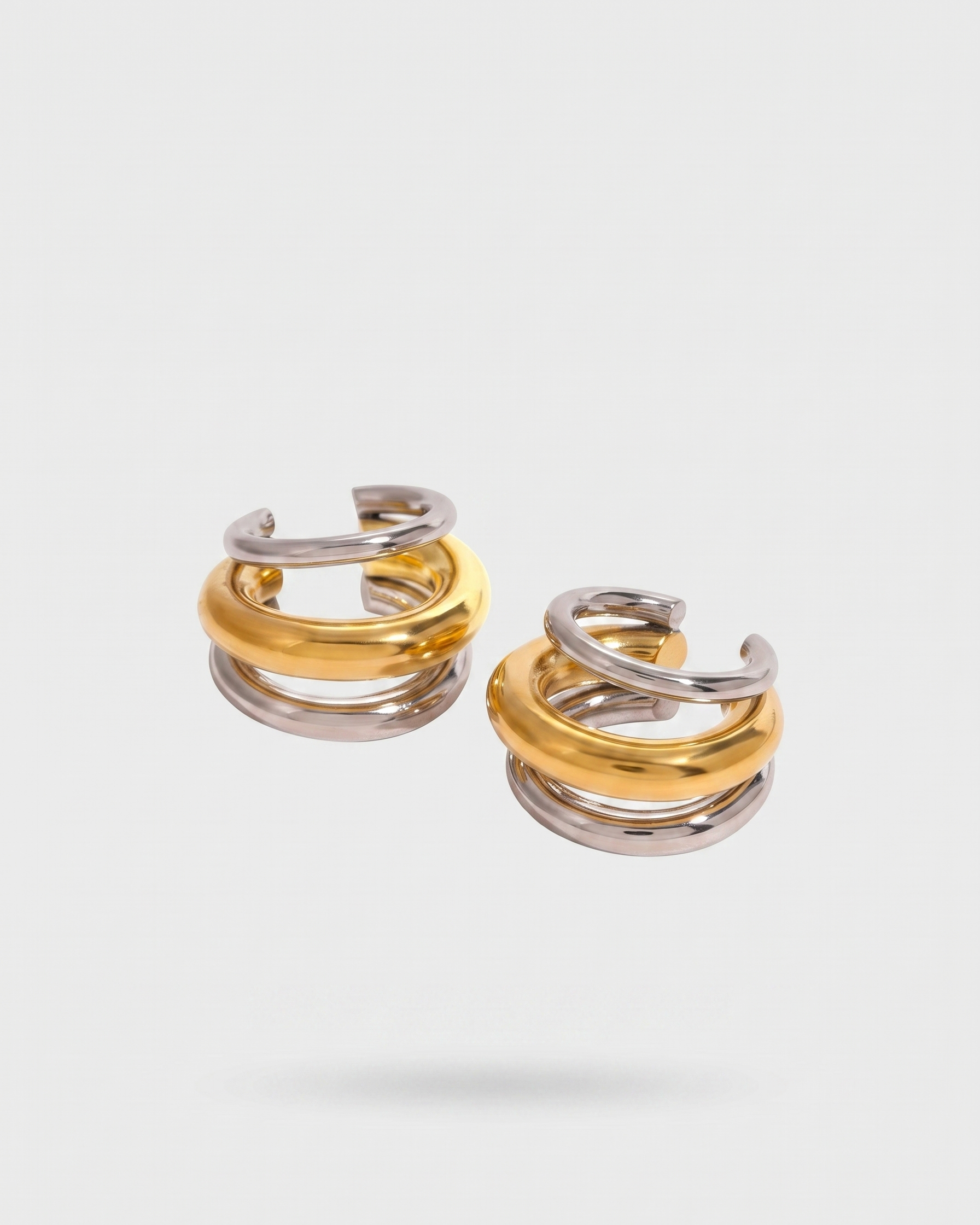 Pair of gold and silver hoop earrings on a light gray background