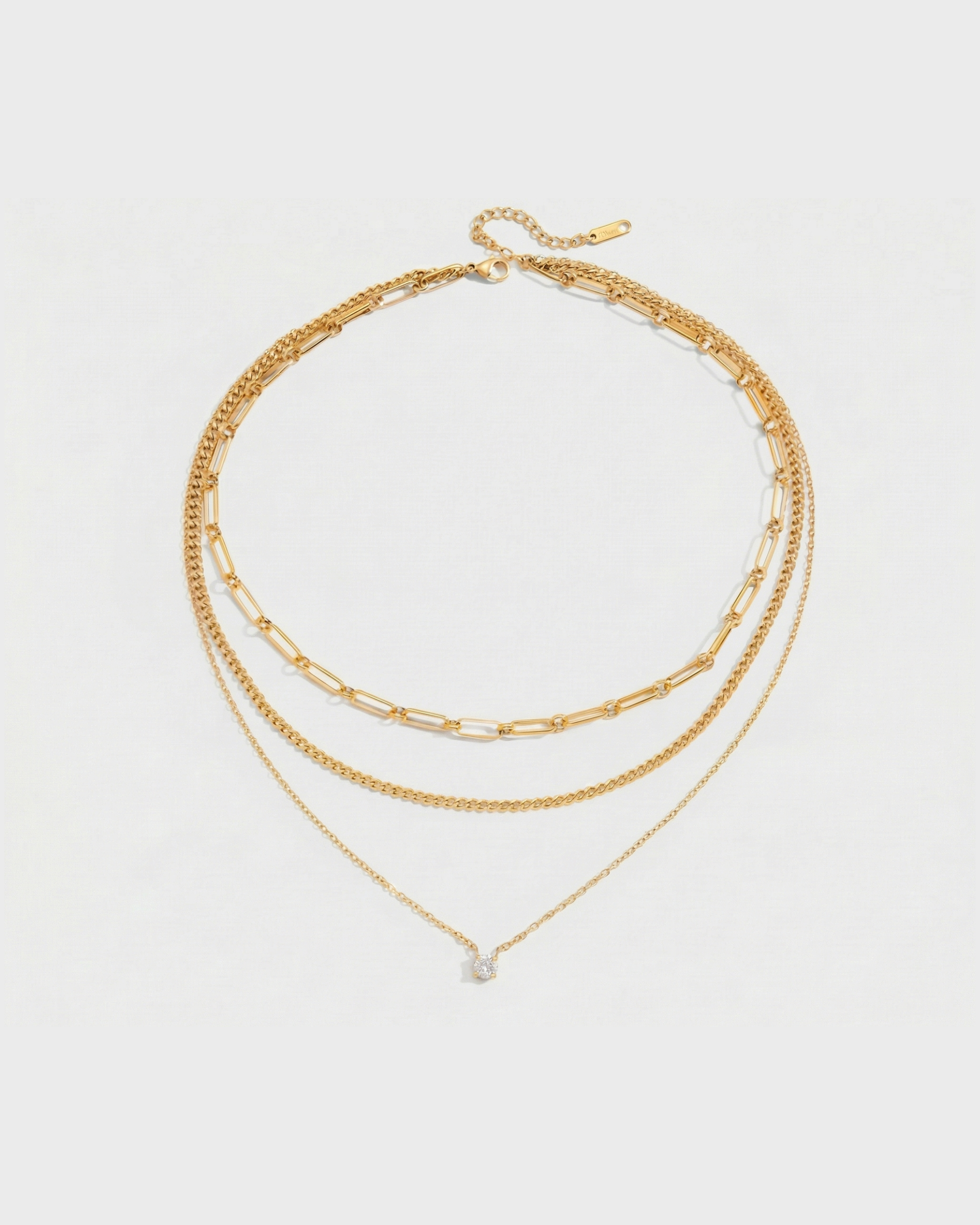 Set of three gold necklaces on a light gray background