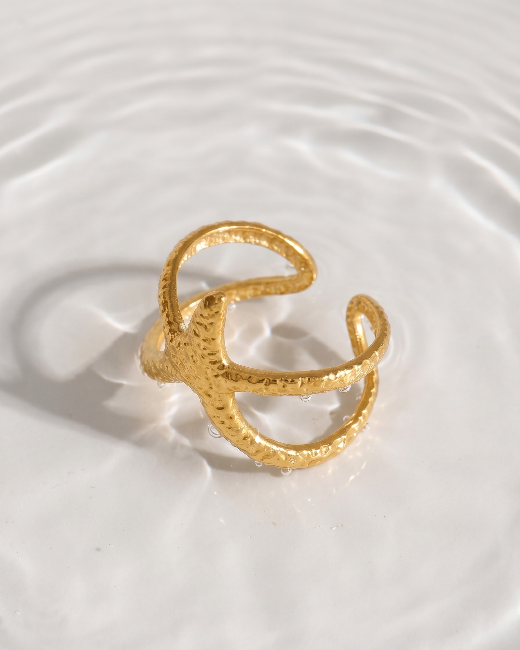 Gold ring on a white surface with water ripples