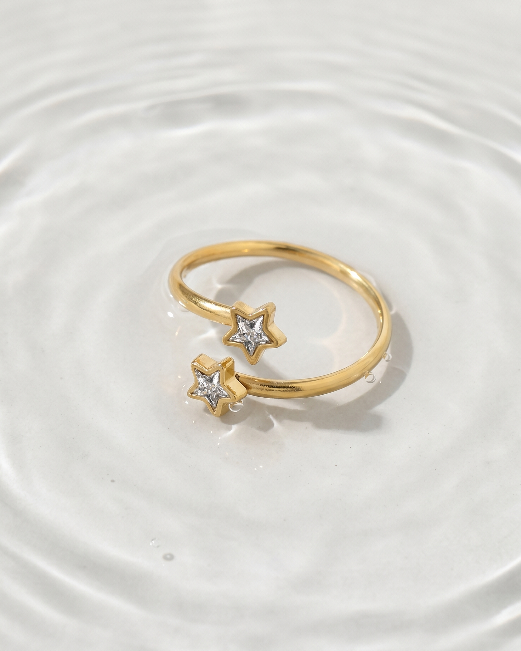 Gold ring with star-shaped stones on a white surface