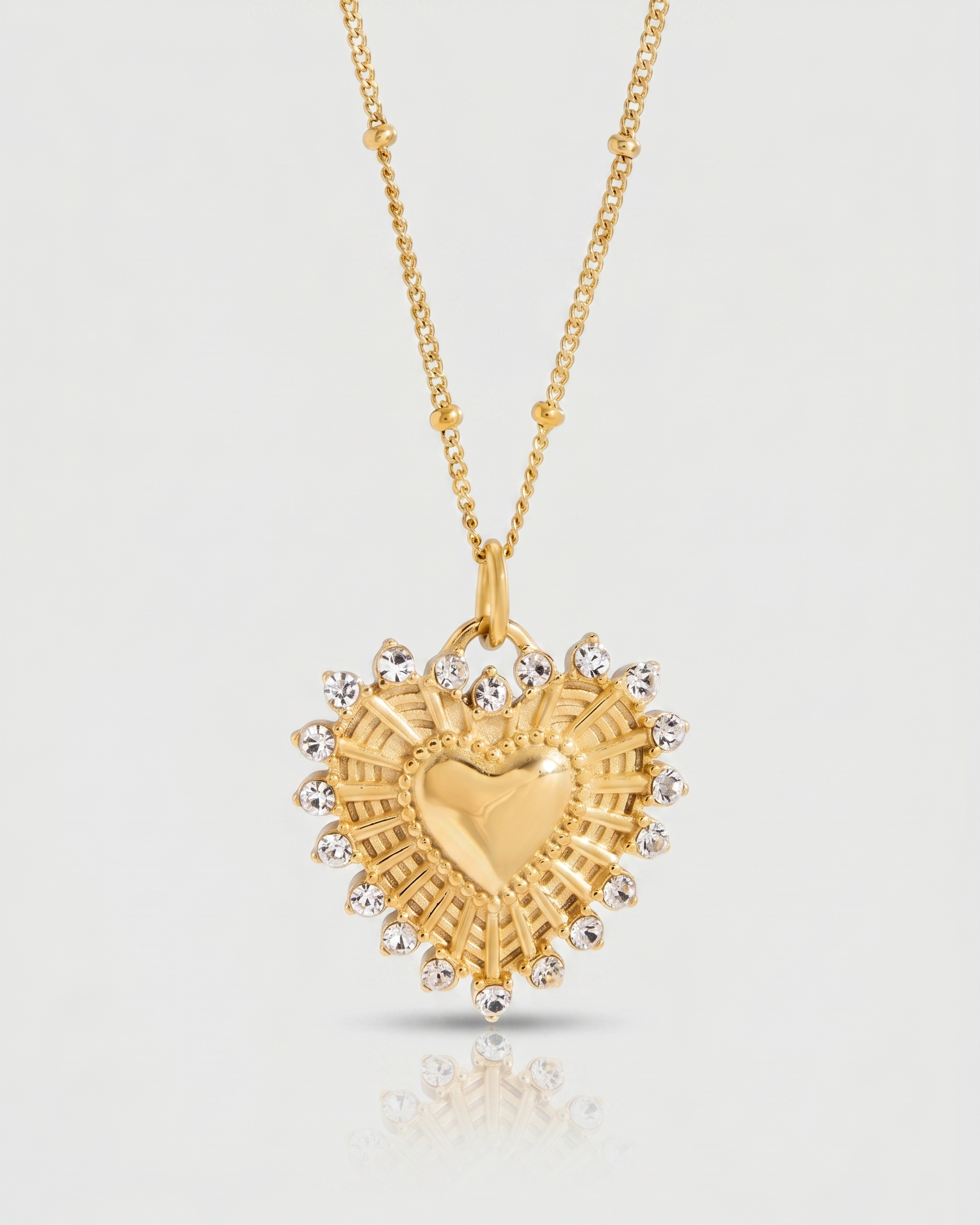 Gold heart-shaped necklace with a chain on a light gray background