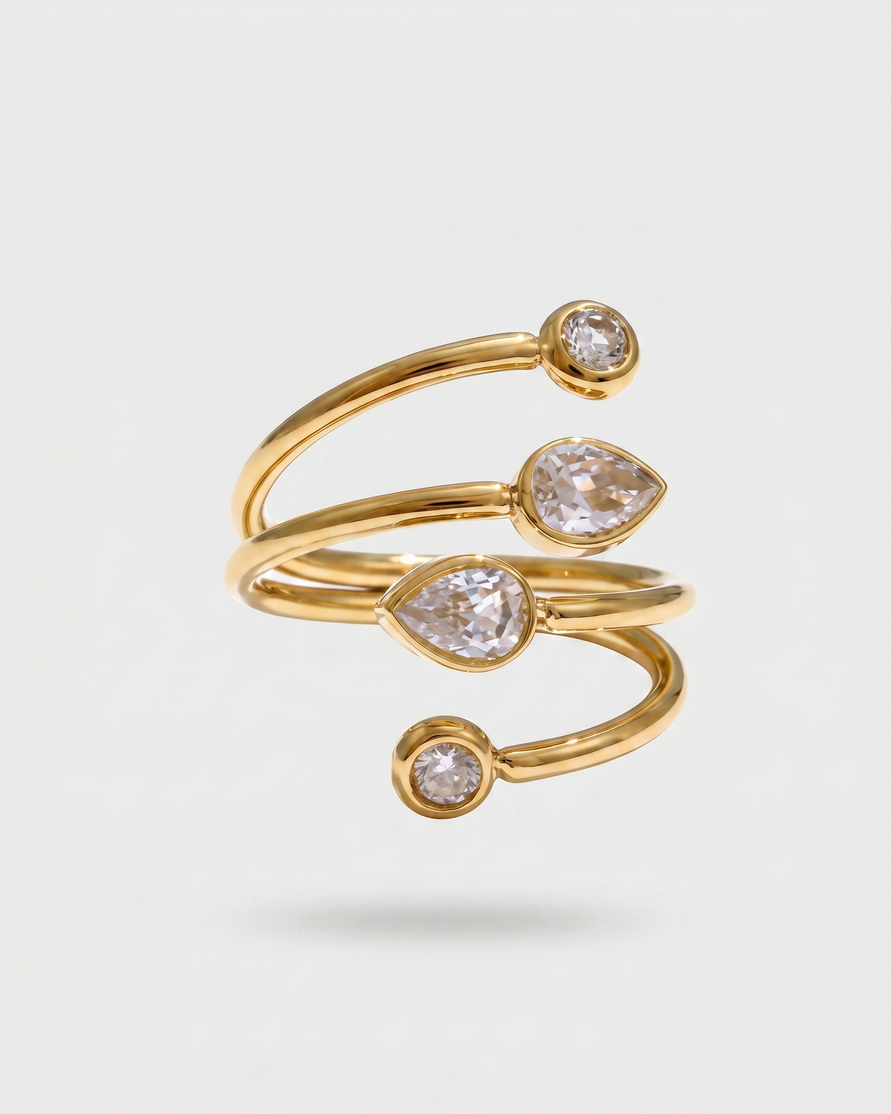 Gold ring with teardrop-shaped gemstones on a light gray background