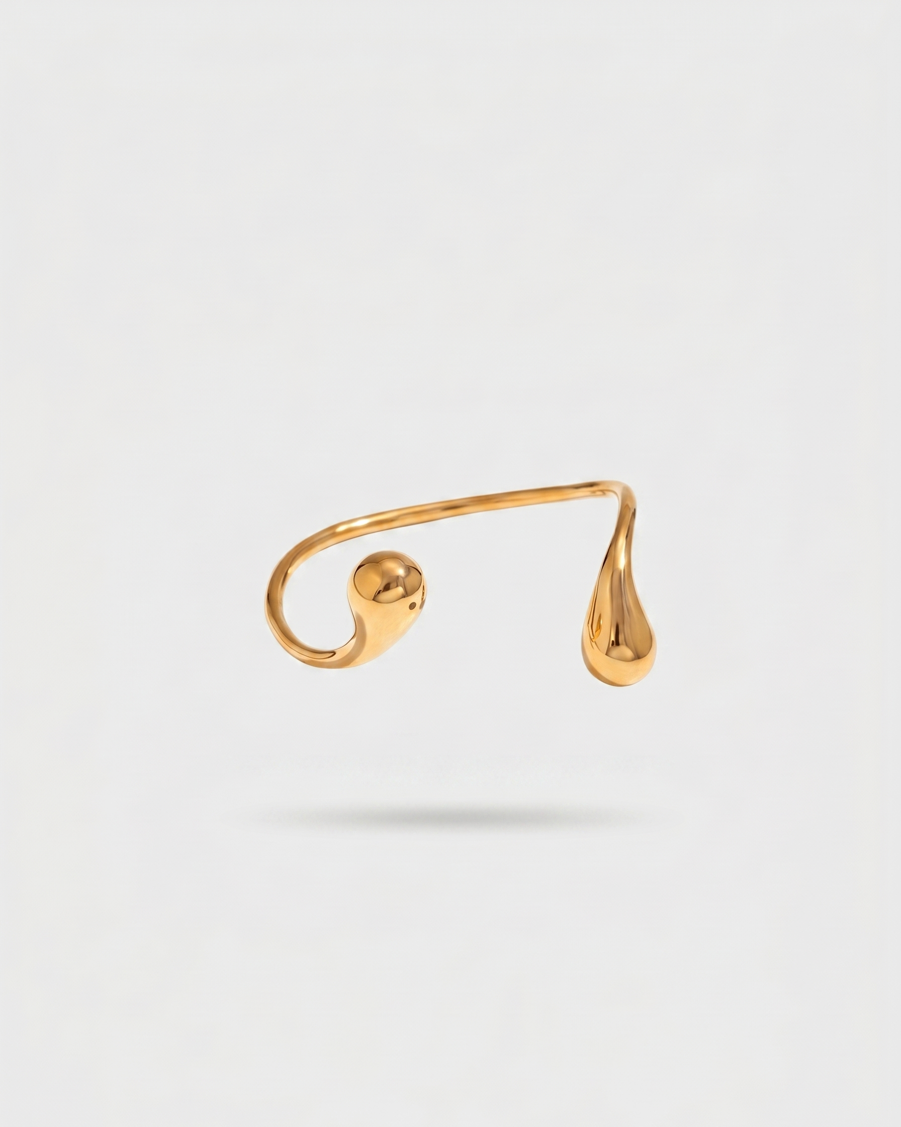Gold ear cuff on a light gray background