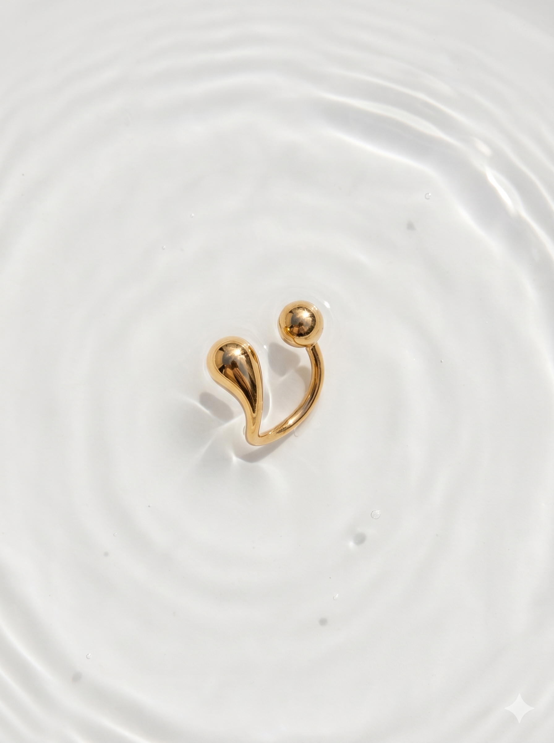 Gold earring on a white background with water ripples