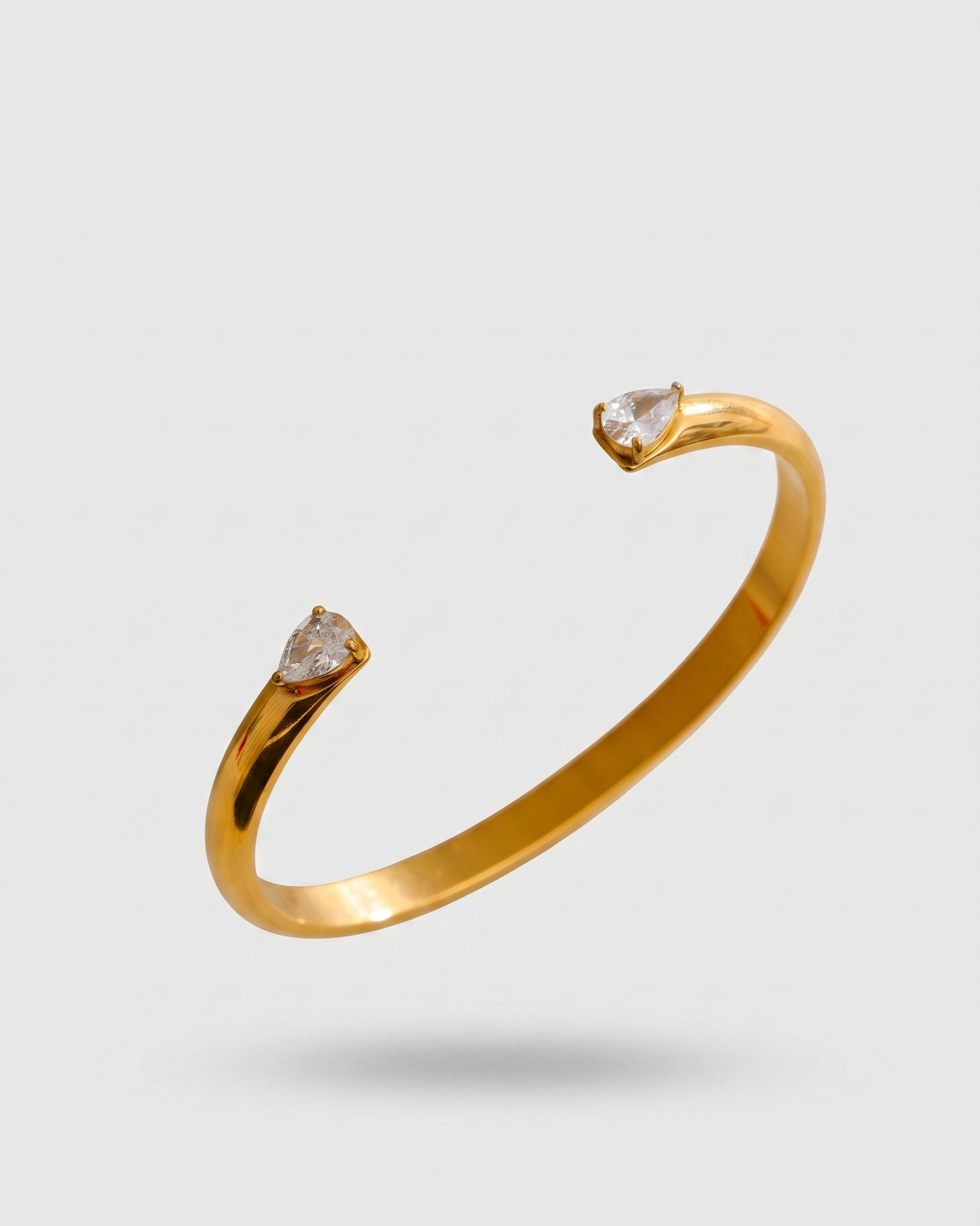 Gold bracelet with heart-shaped gemstones on a light gray background