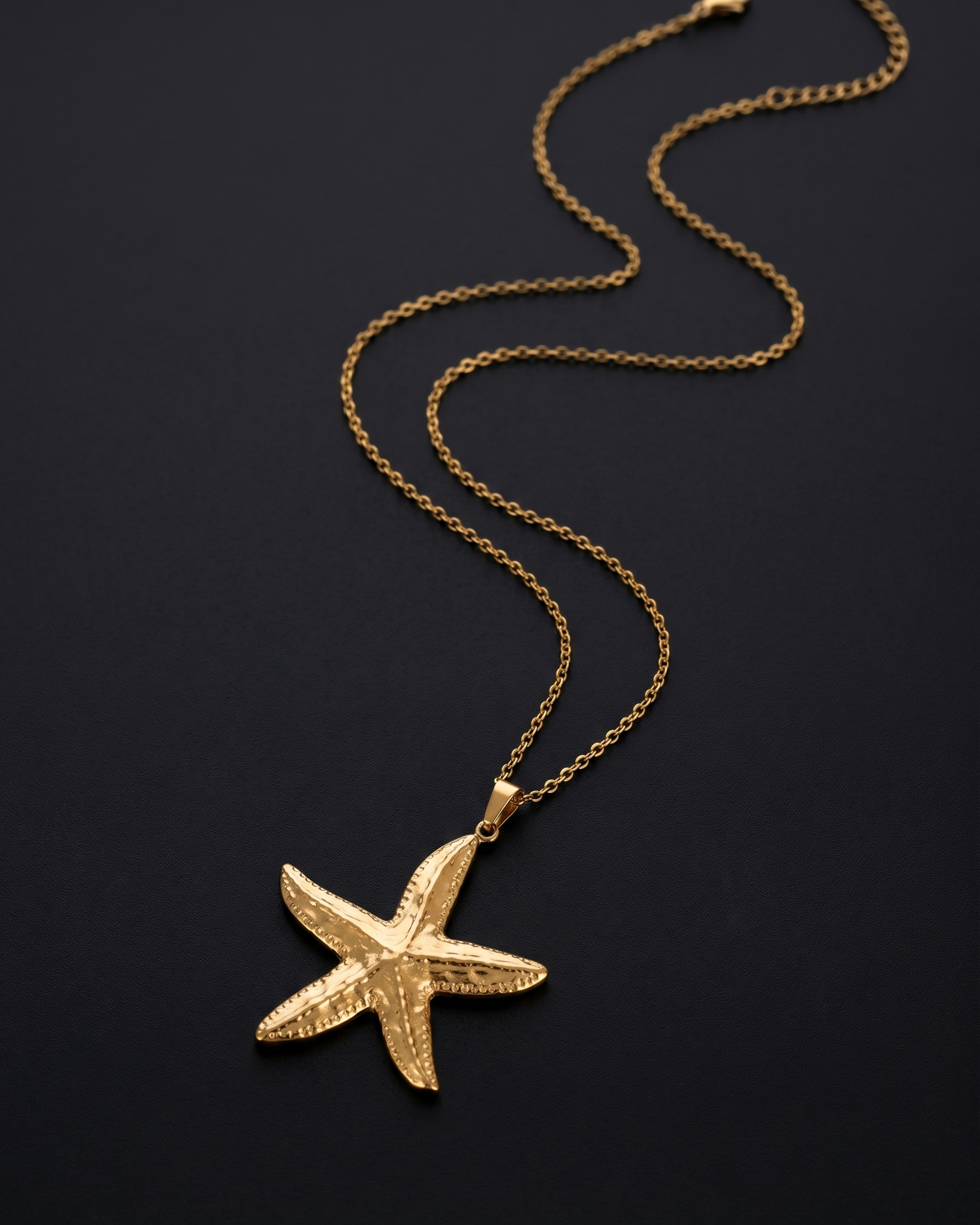 Gold starfish pendant necklace on a black background