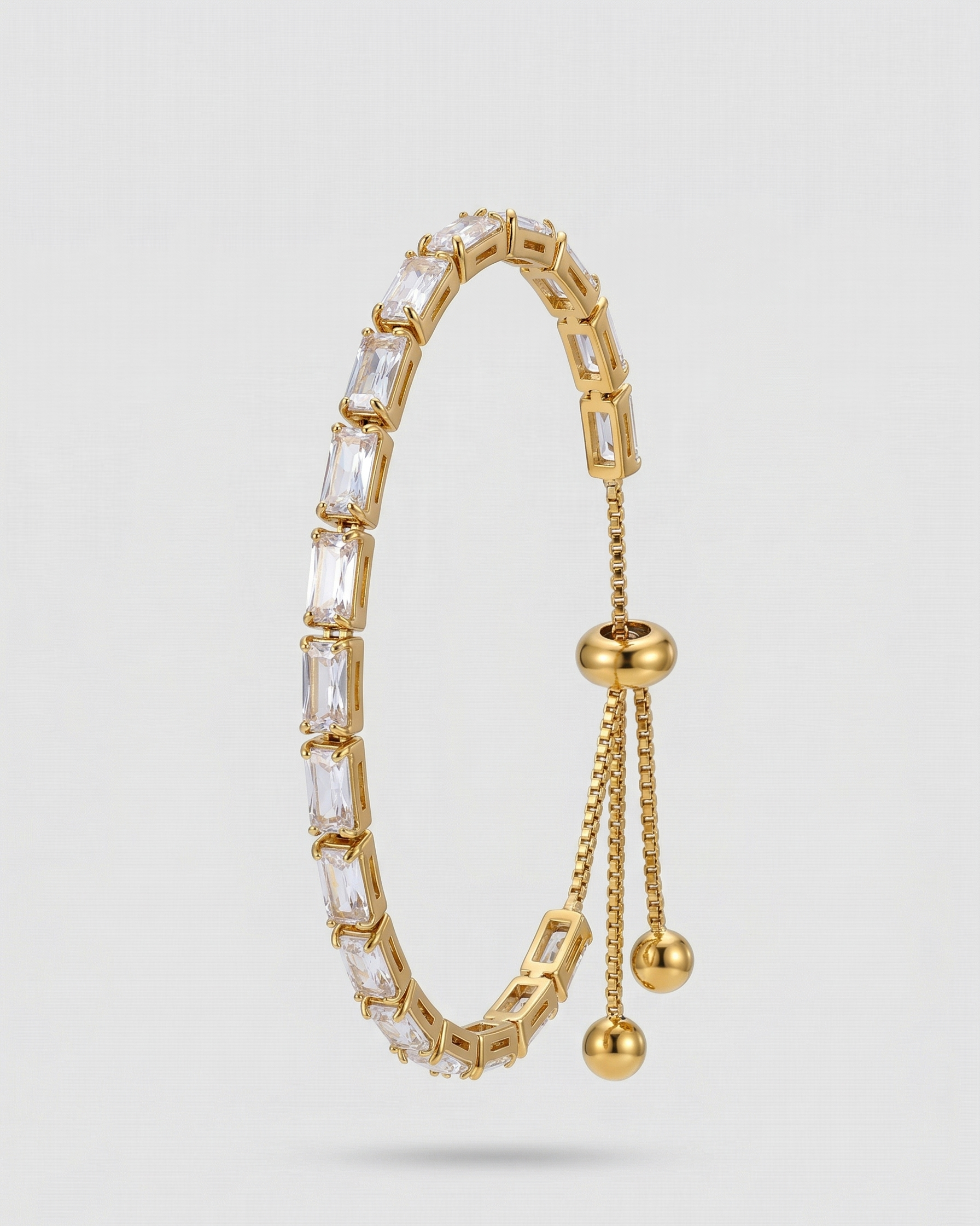Gold bracelet with clear gemstones on a light gray background
