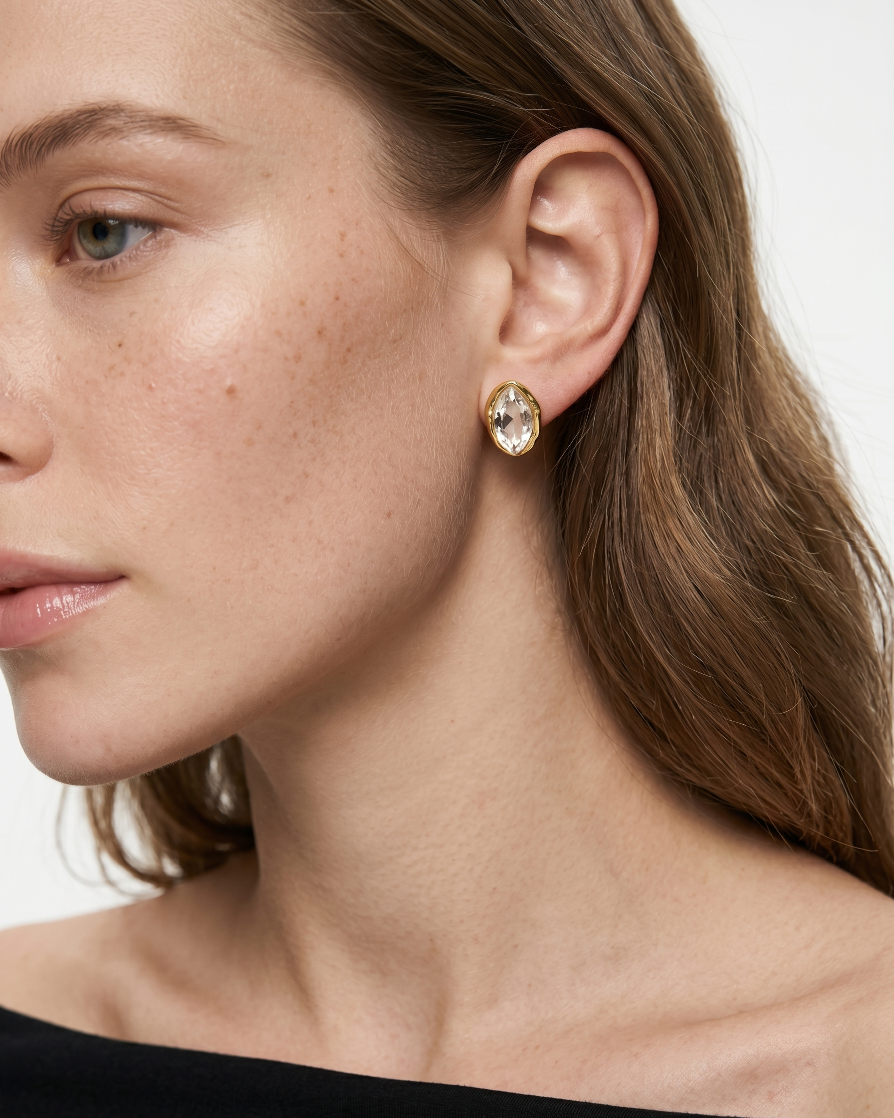 Close-up of a woman wearing gold earrings with a neutral background