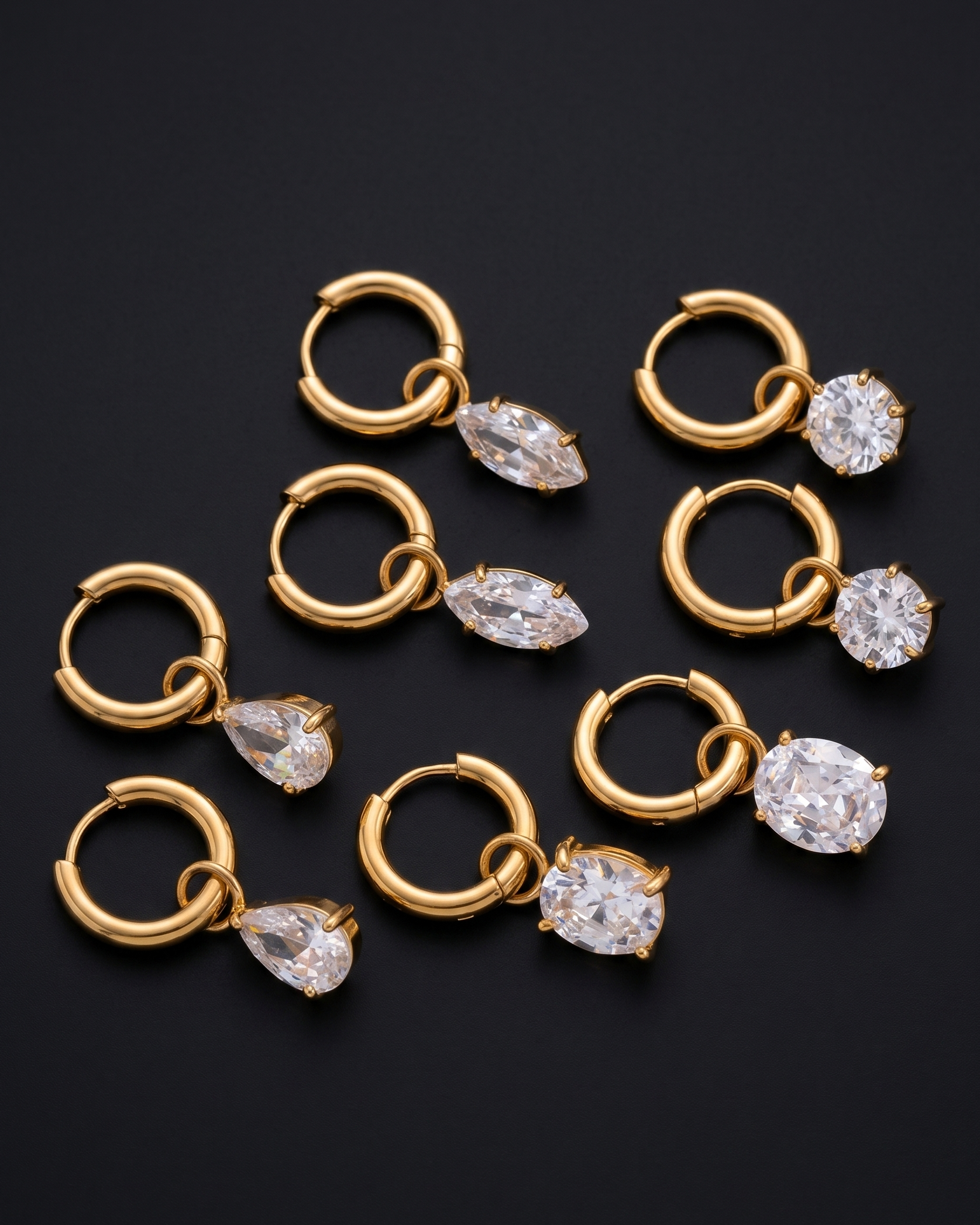 Gold hoop earrings with clear gemstones on a black background