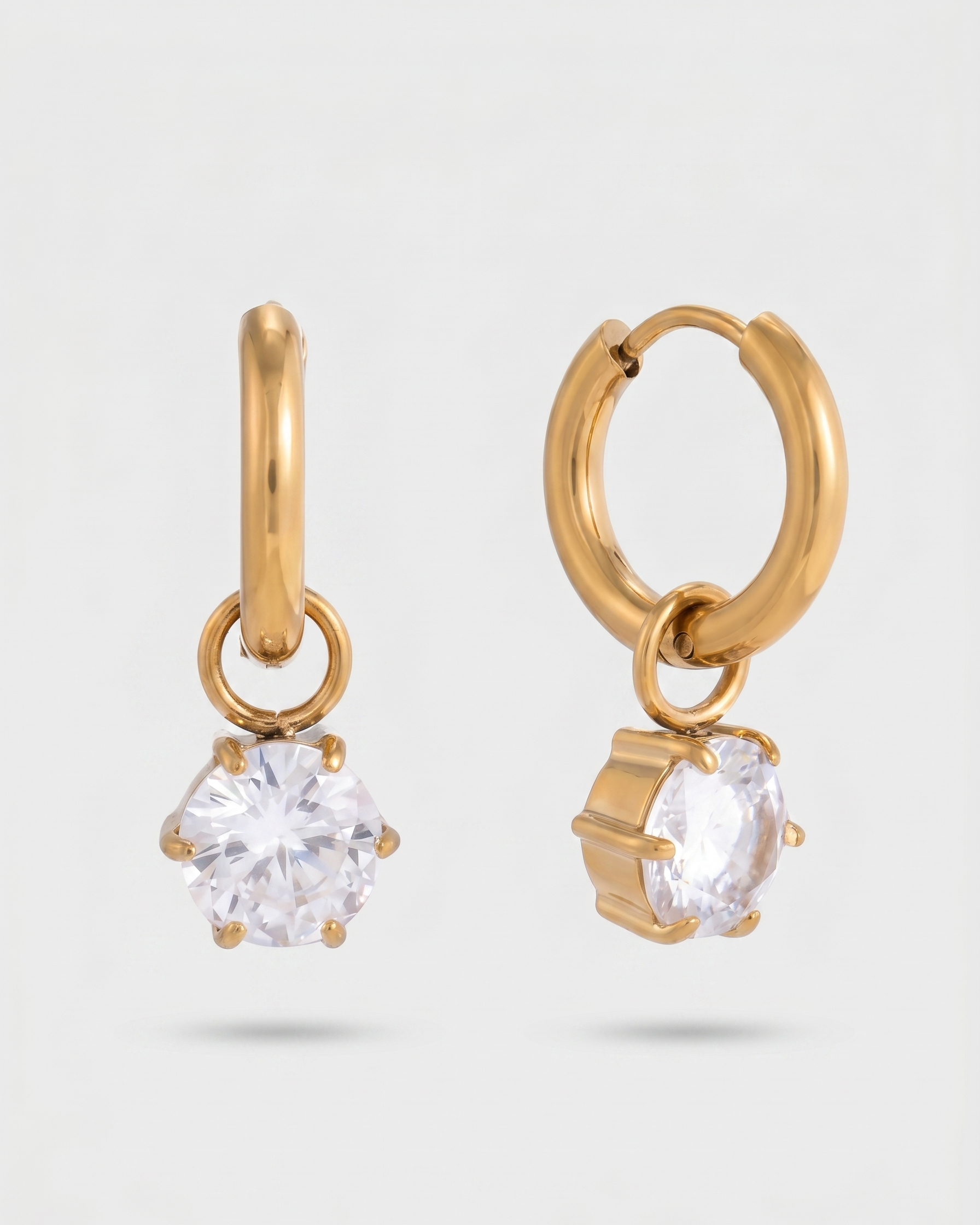 Gold hoop earrings with clear gemstones on a light gray background