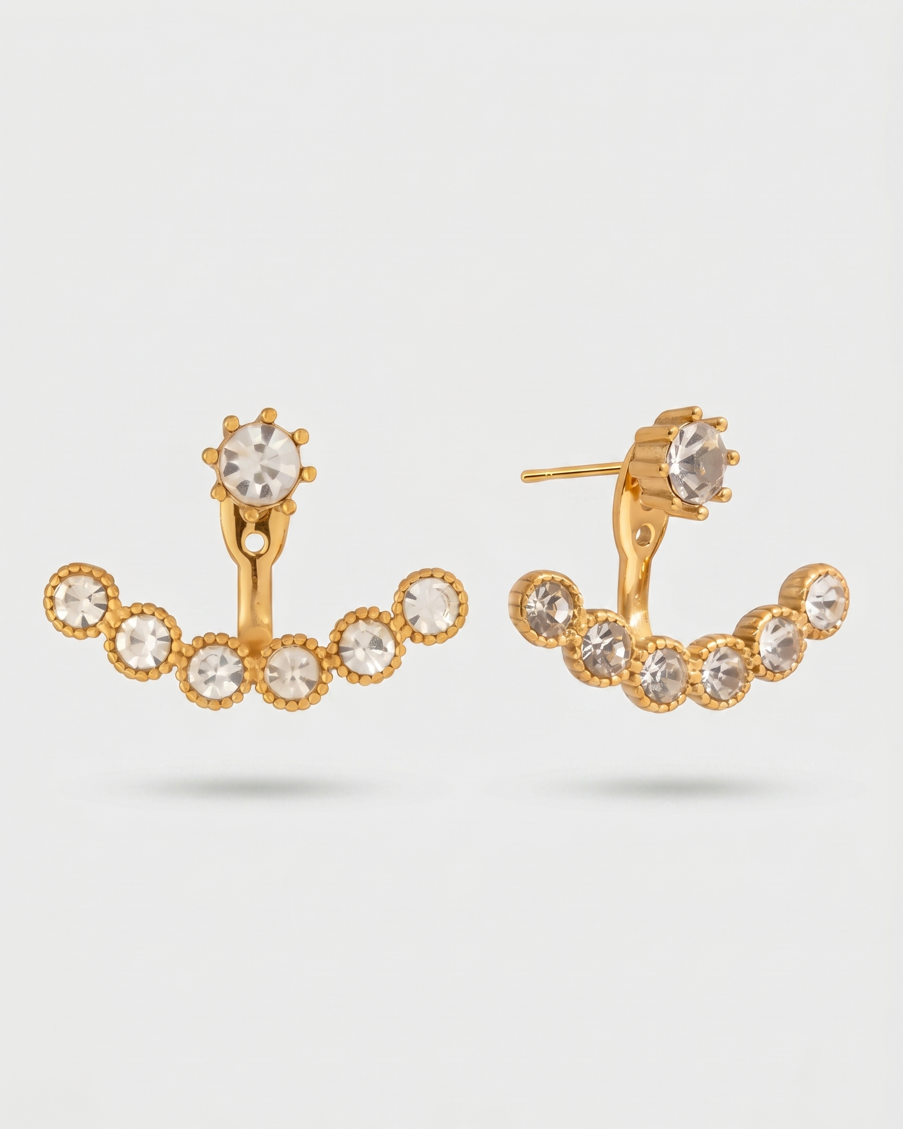 Gold hoop earrings with clear gemstones on a light gray background