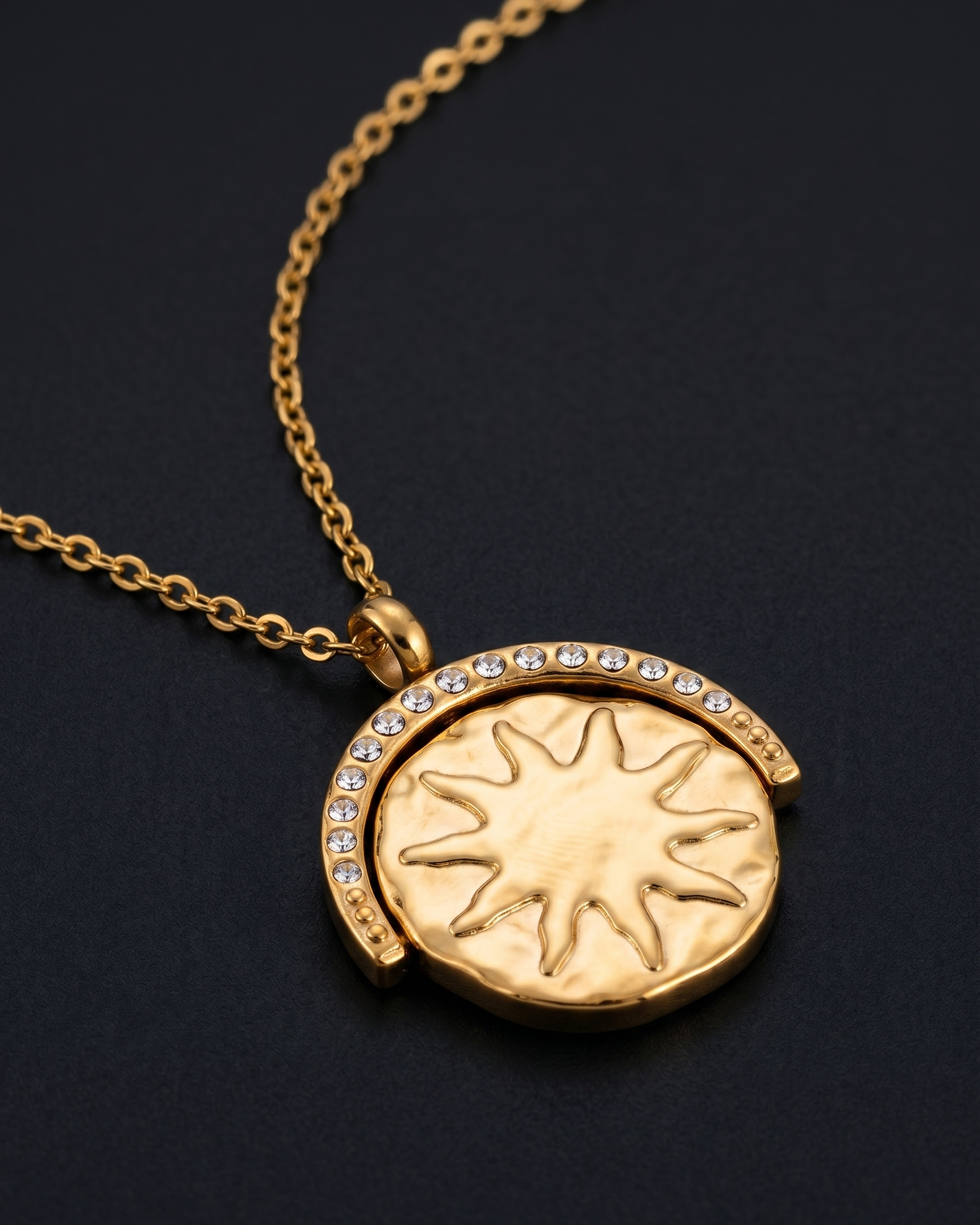 Gold necklace with a sun design pendant on a black background