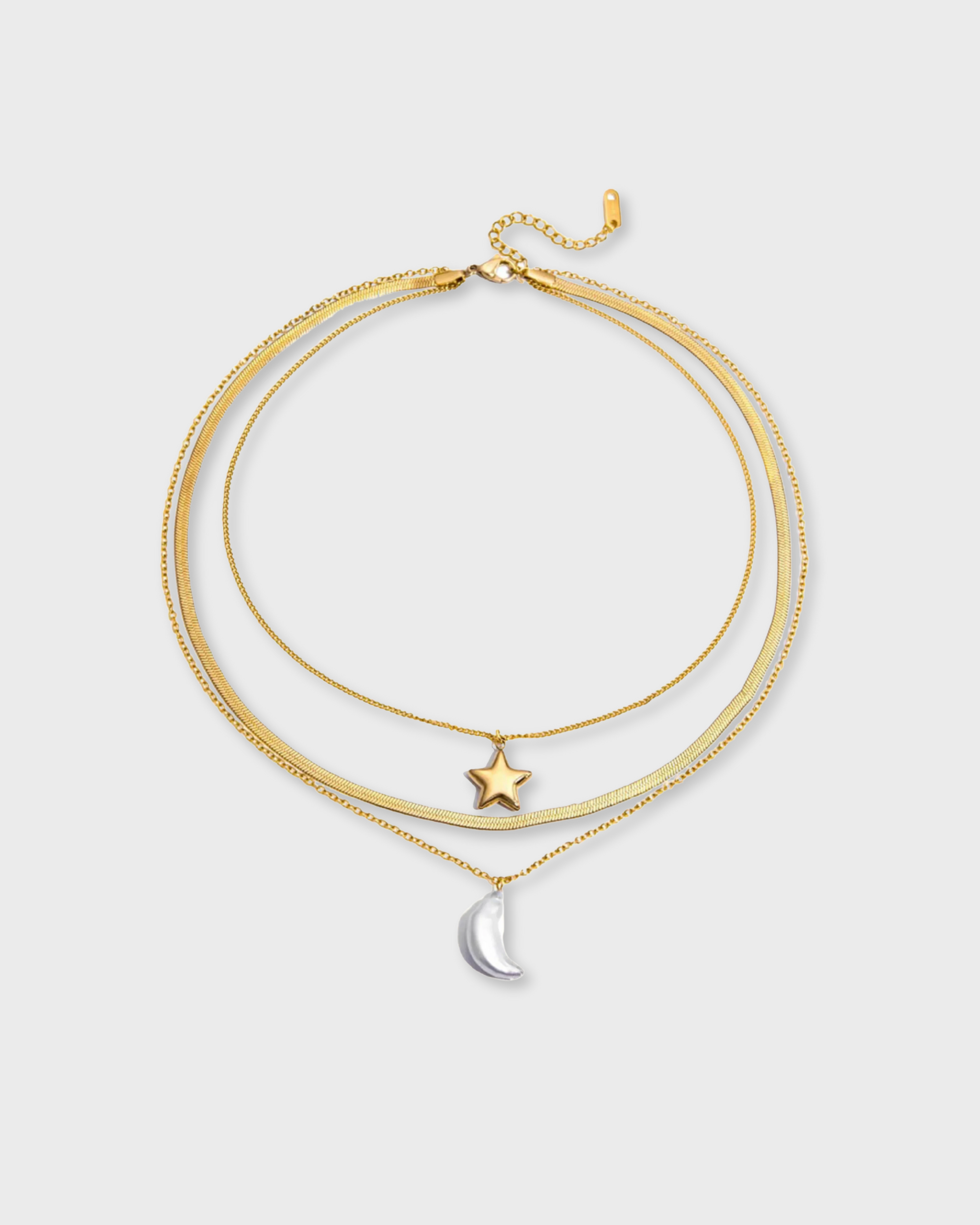 Gold necklace with star and moon pendants on a light gray background