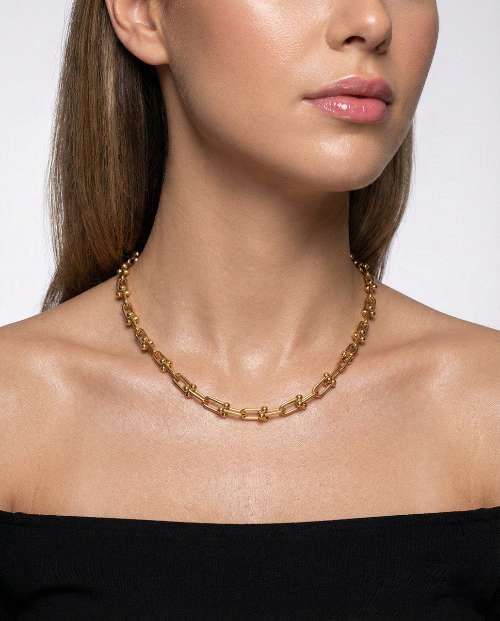 Gold chain necklace worn by a model on a plain background