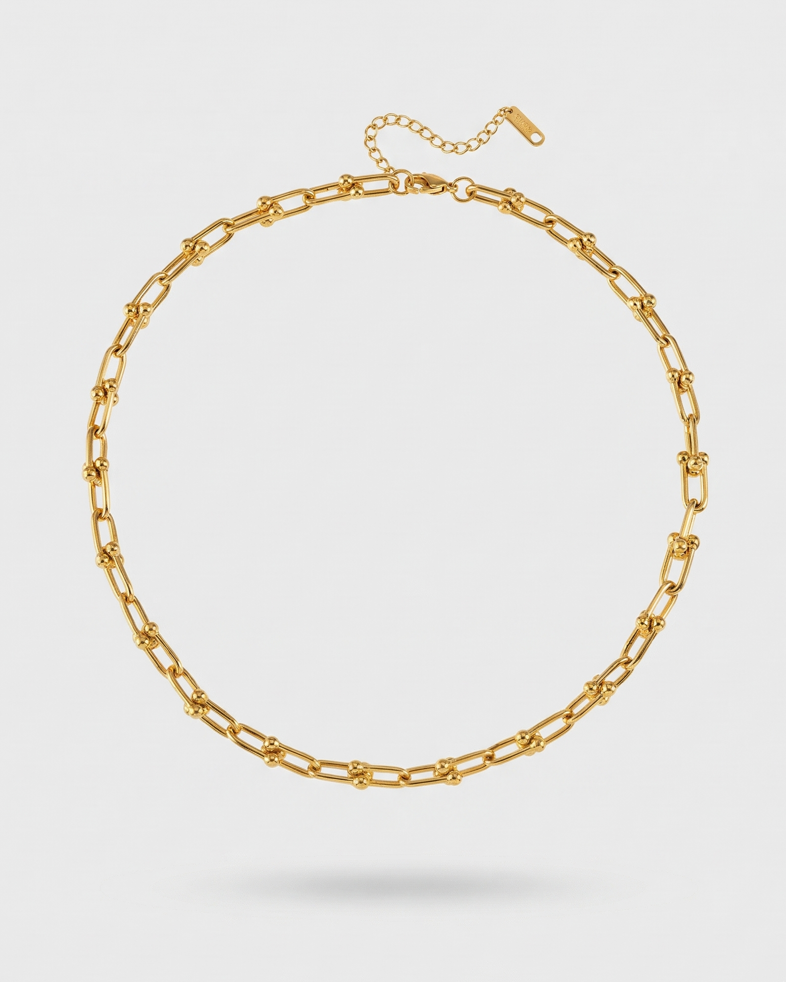 Gold chain necklace on a light gray background