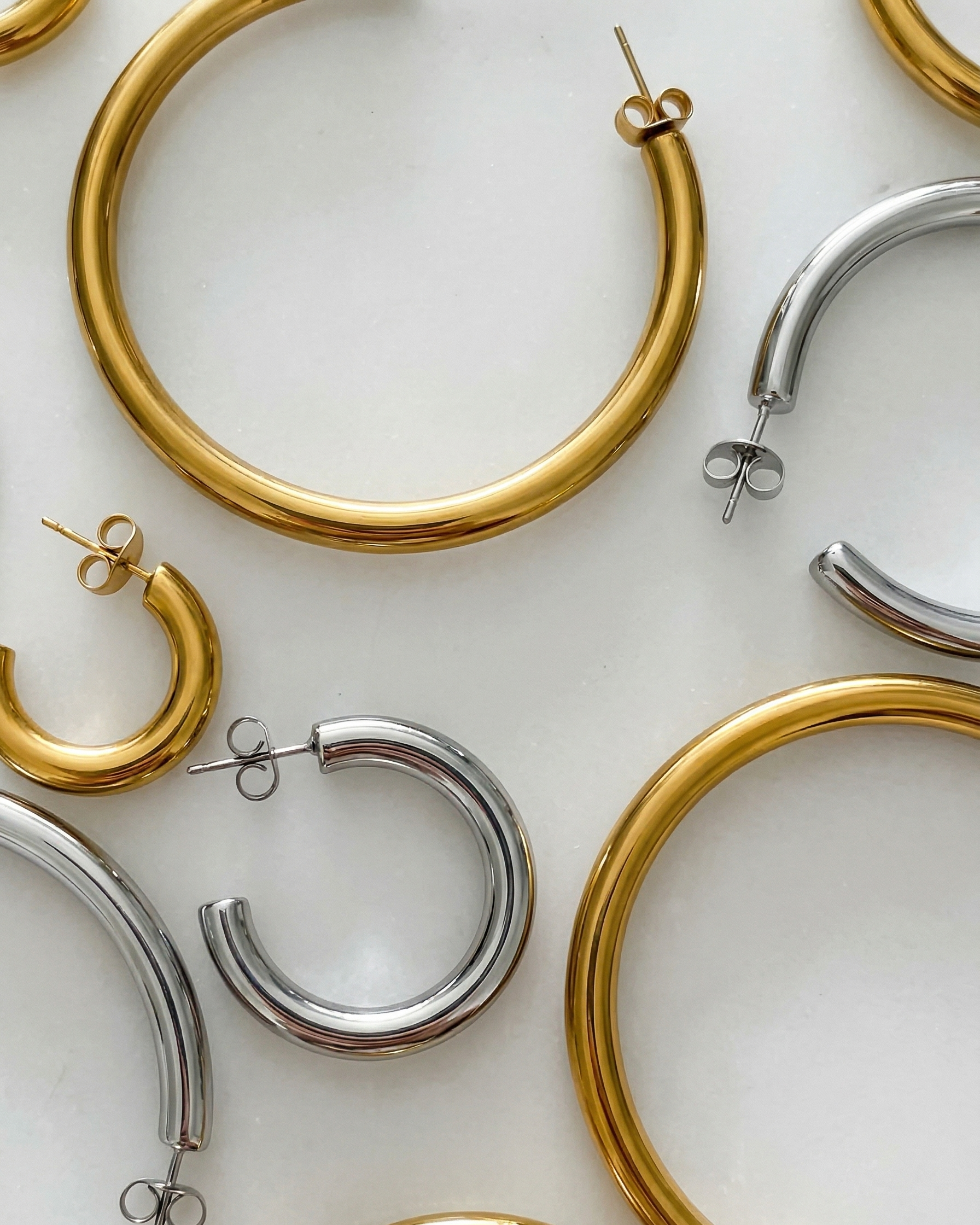 Gold and silver hoop earrings on a light background