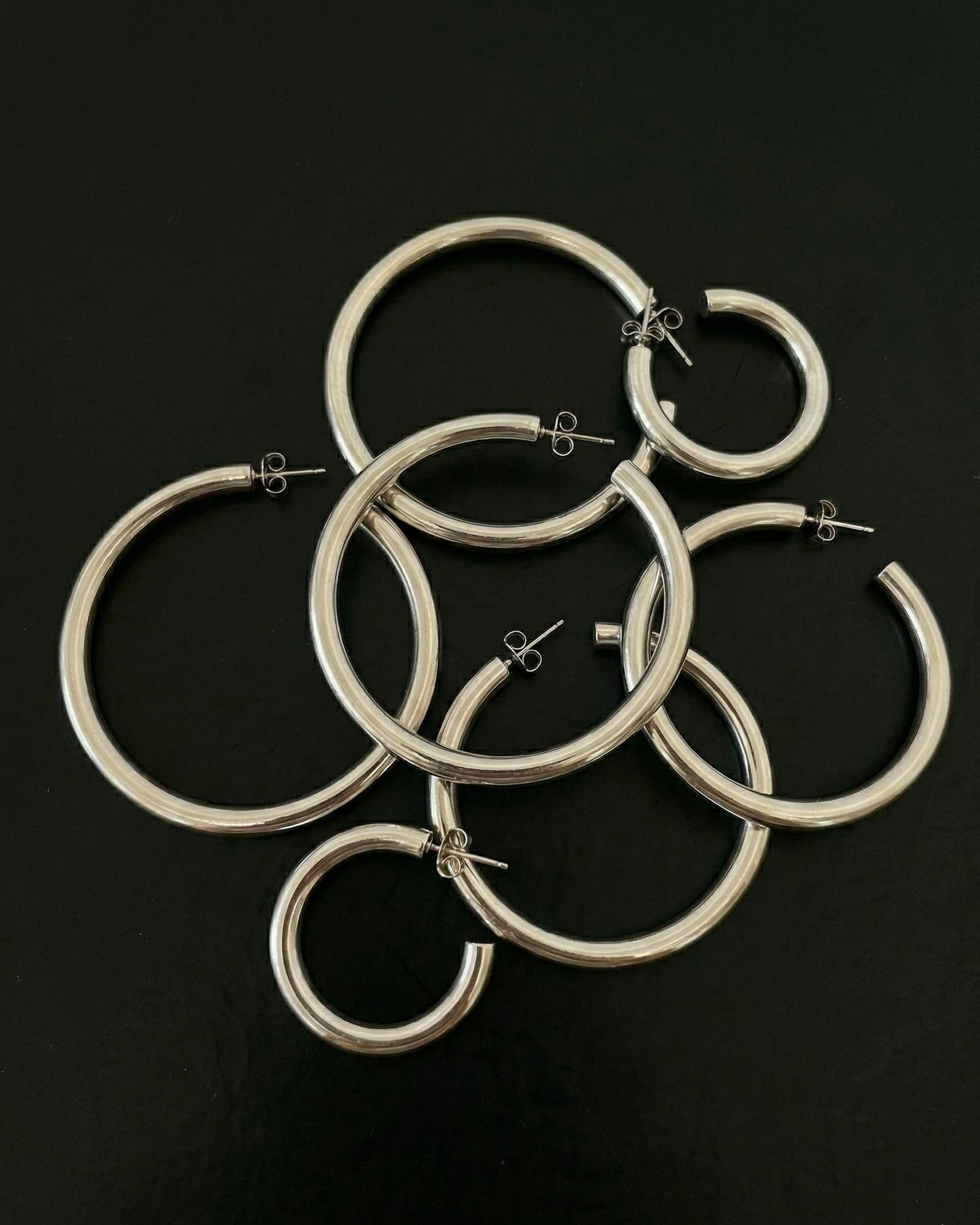 Silver hoop earrings on a black background