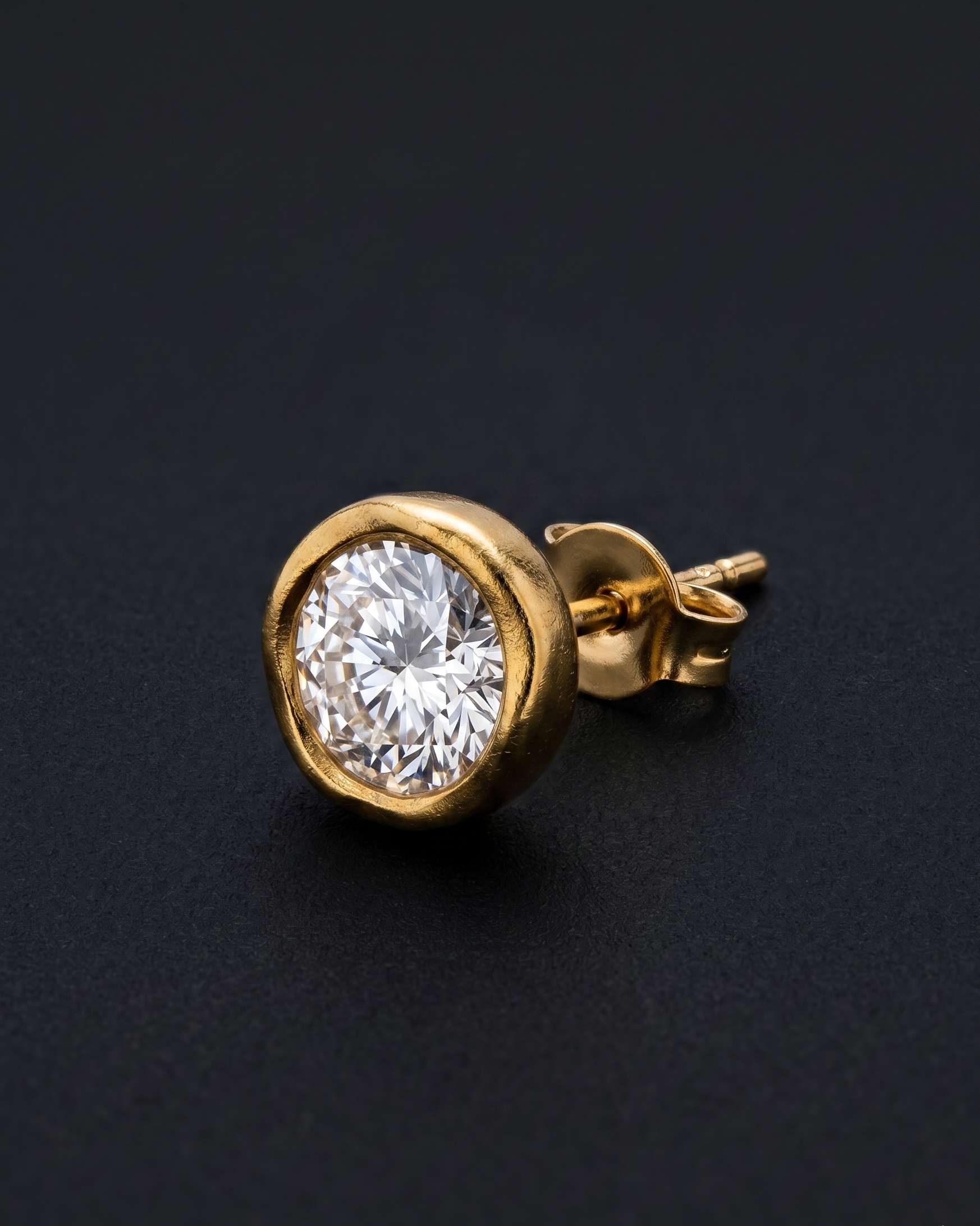 Gold earring with a clear gemstone on a black background