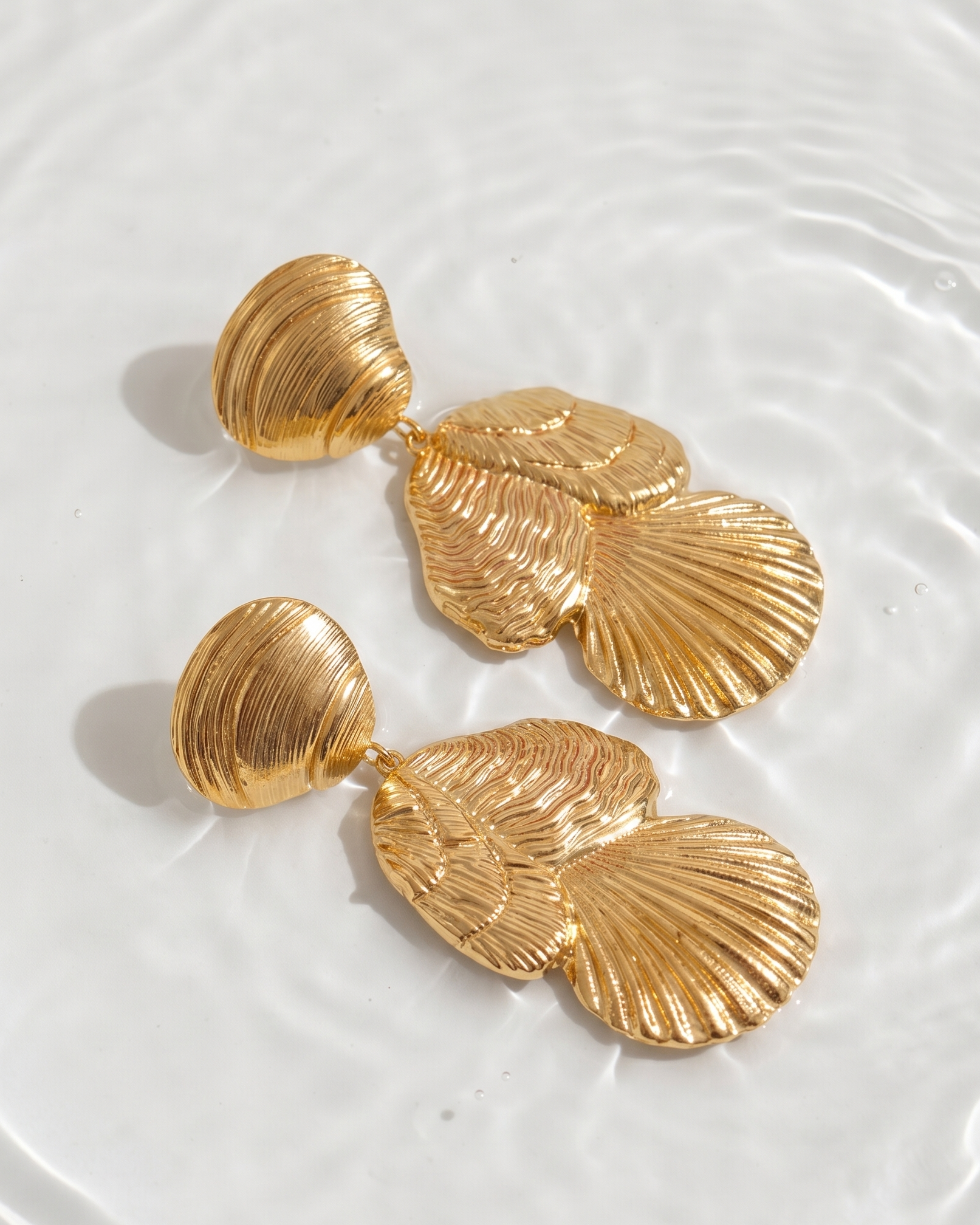 Gold shell-shaped earrings on a white surface