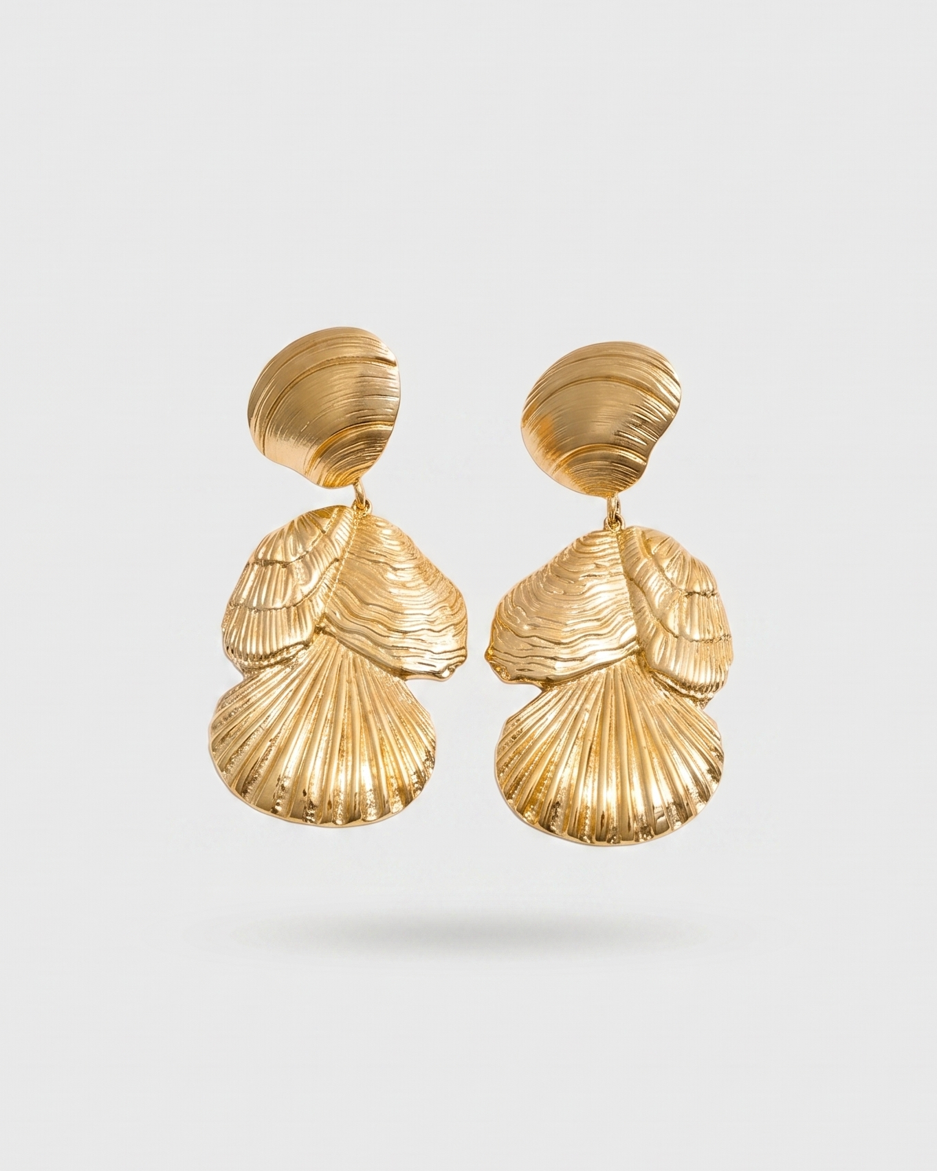 Pair of gold shell-shaped earrings on a light gray background