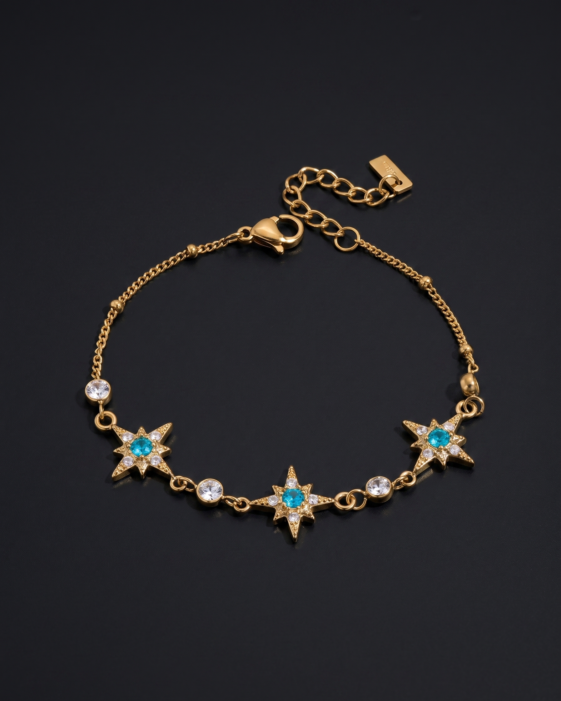 Gold bracelet with star-shaped charms and blue stones on a black background