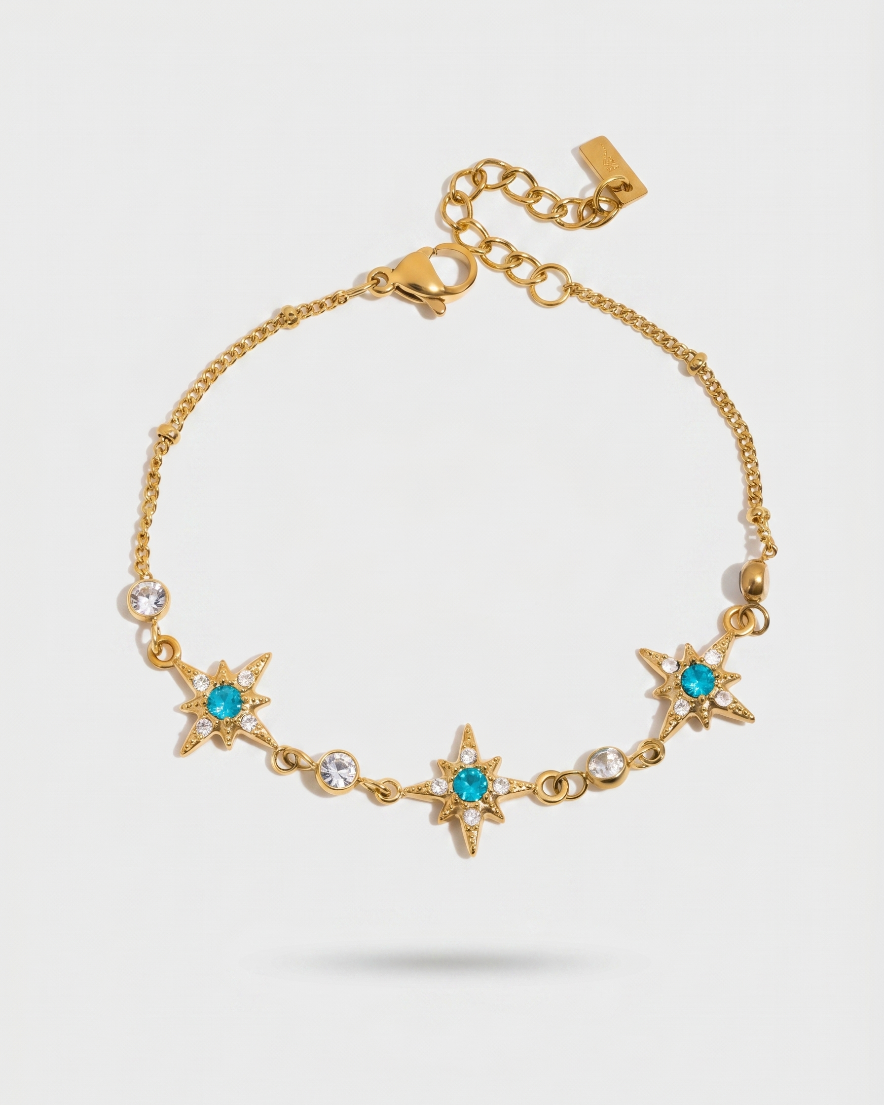 Gold bracelet with star-shaped charms and blue stones on a white background