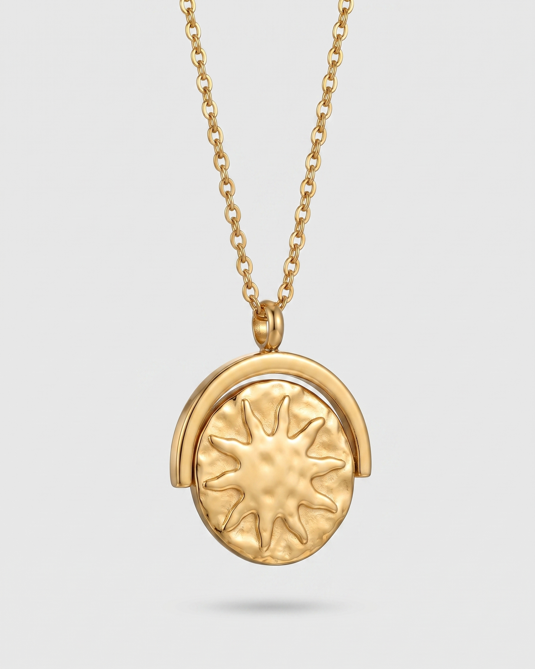 Gold necklace with a sun-shaped pendant on a light gray background