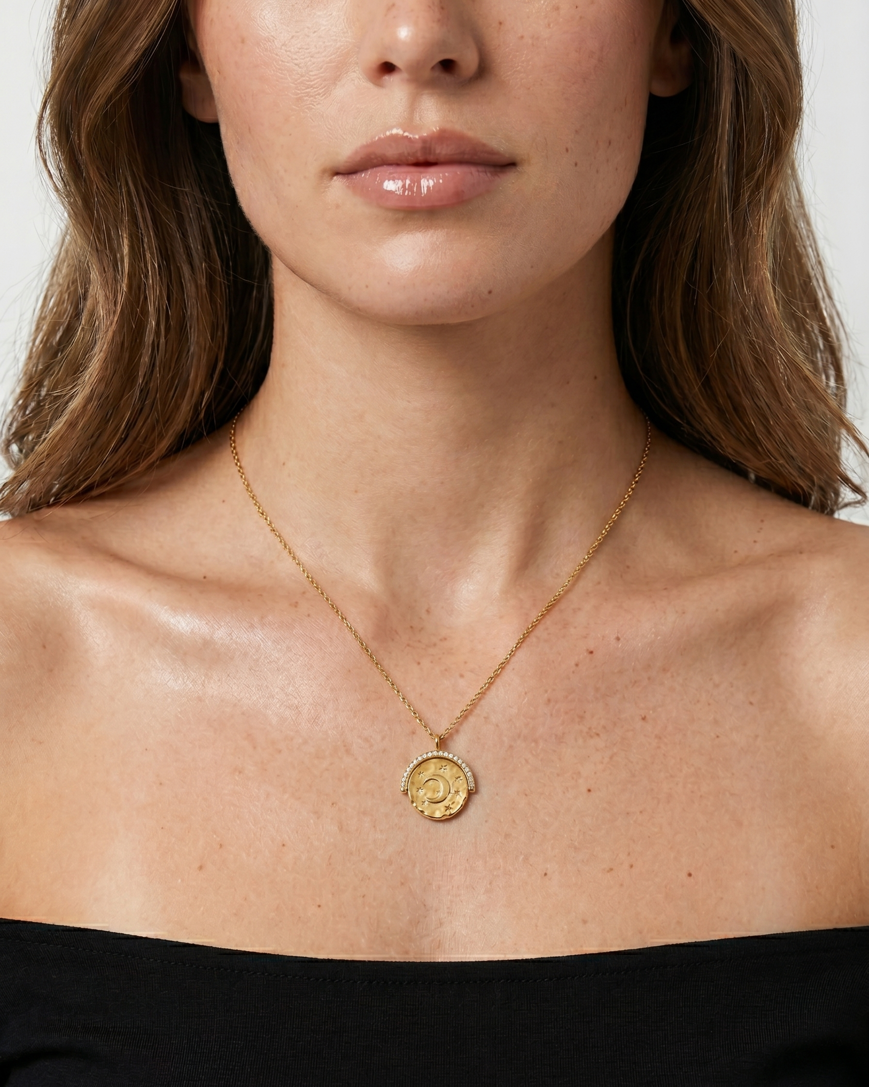 Close-up of a woman wearing a gold necklace with a pendant on a white background