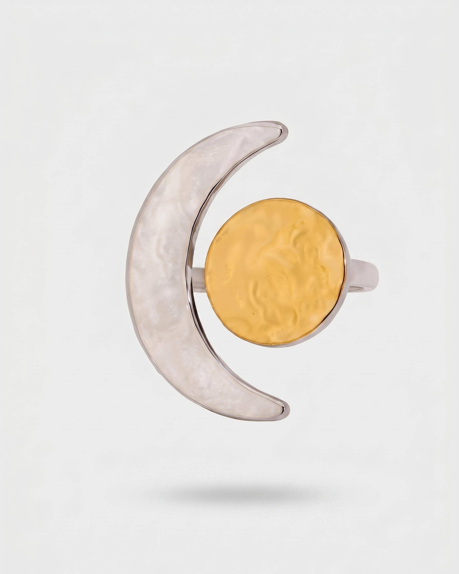 Silver crescent moon-shaped ring with a gold circle on a light gray background