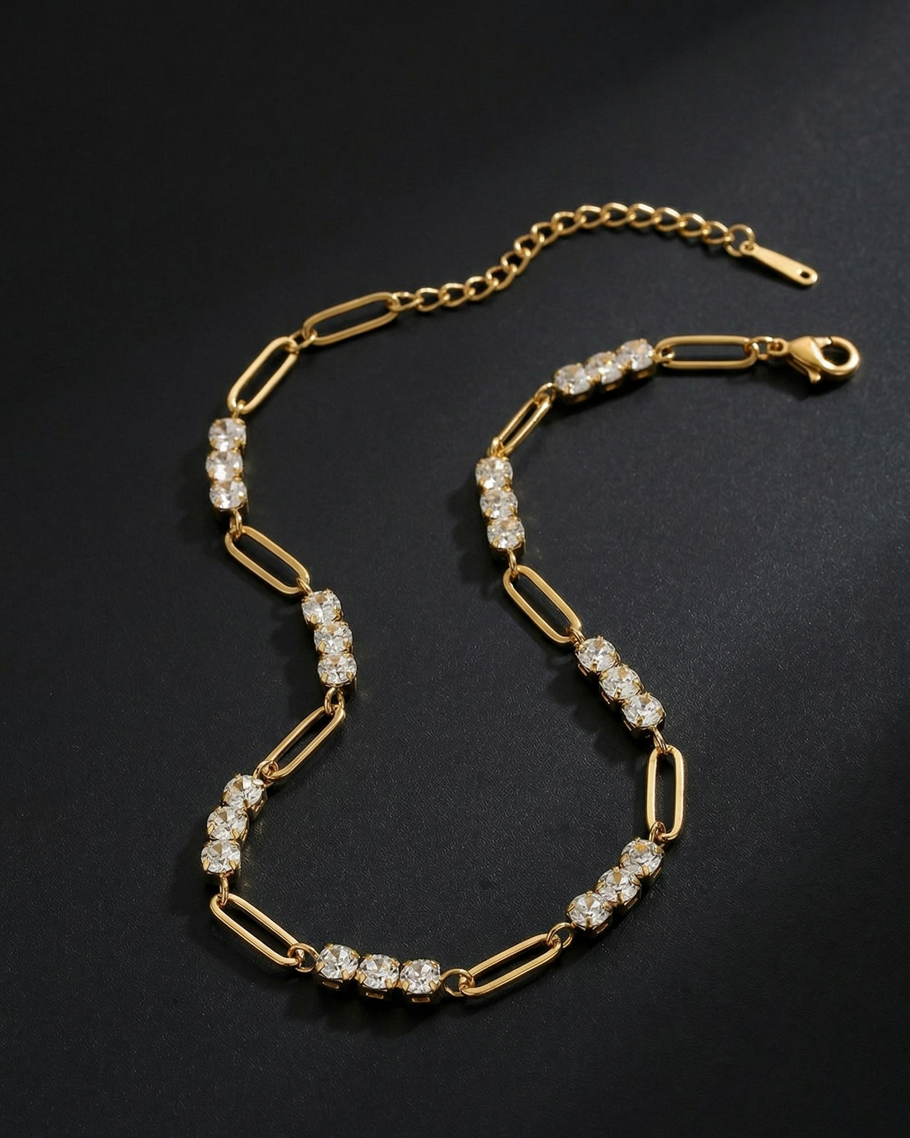 Gold chain necklace with diamond-like beads on a dark background