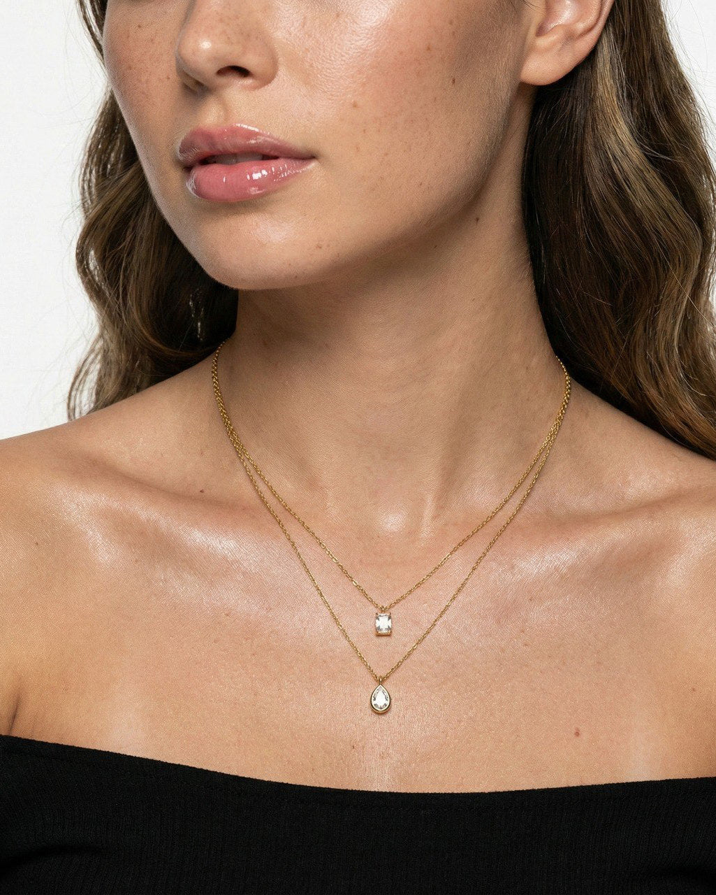 Close-up of a woman wearing a gold necklace with a pendant on a white background