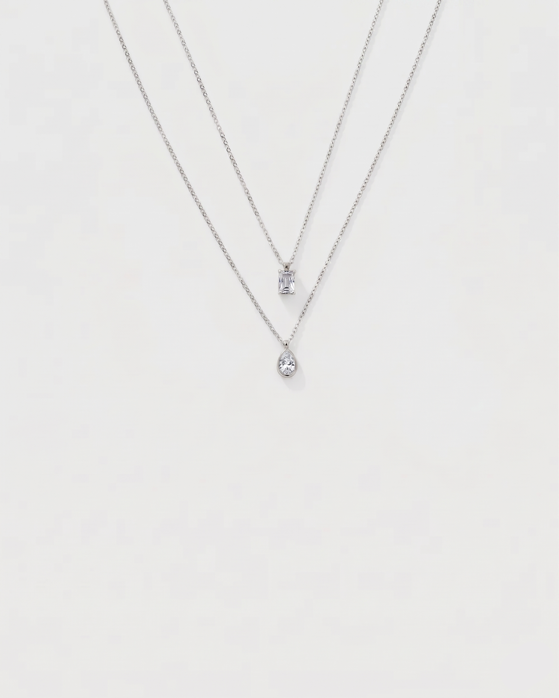 Silver necklace with a small pendant on a light gray background