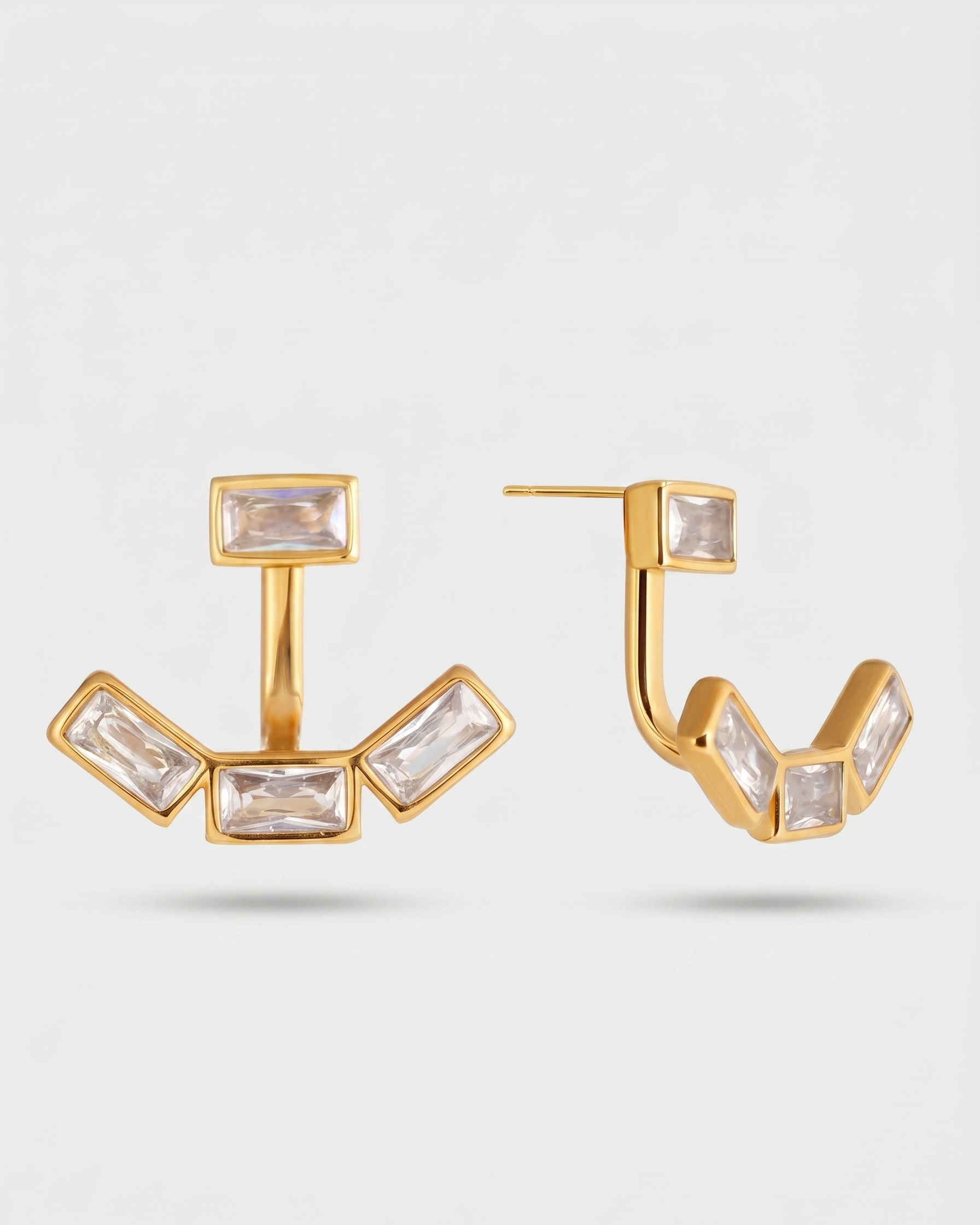 Gold hoop earrings with clear gemstones on a light gray background