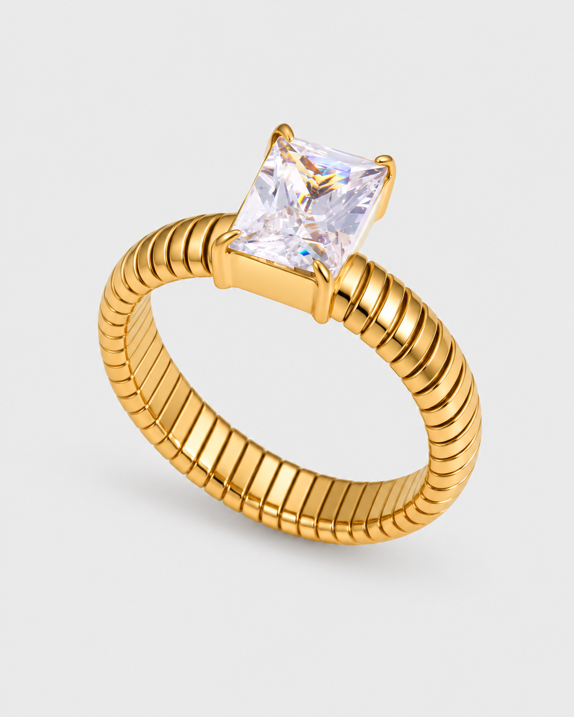 A gold snake-style ring with a princess-cut clear gemstone, shown on a light gray background.