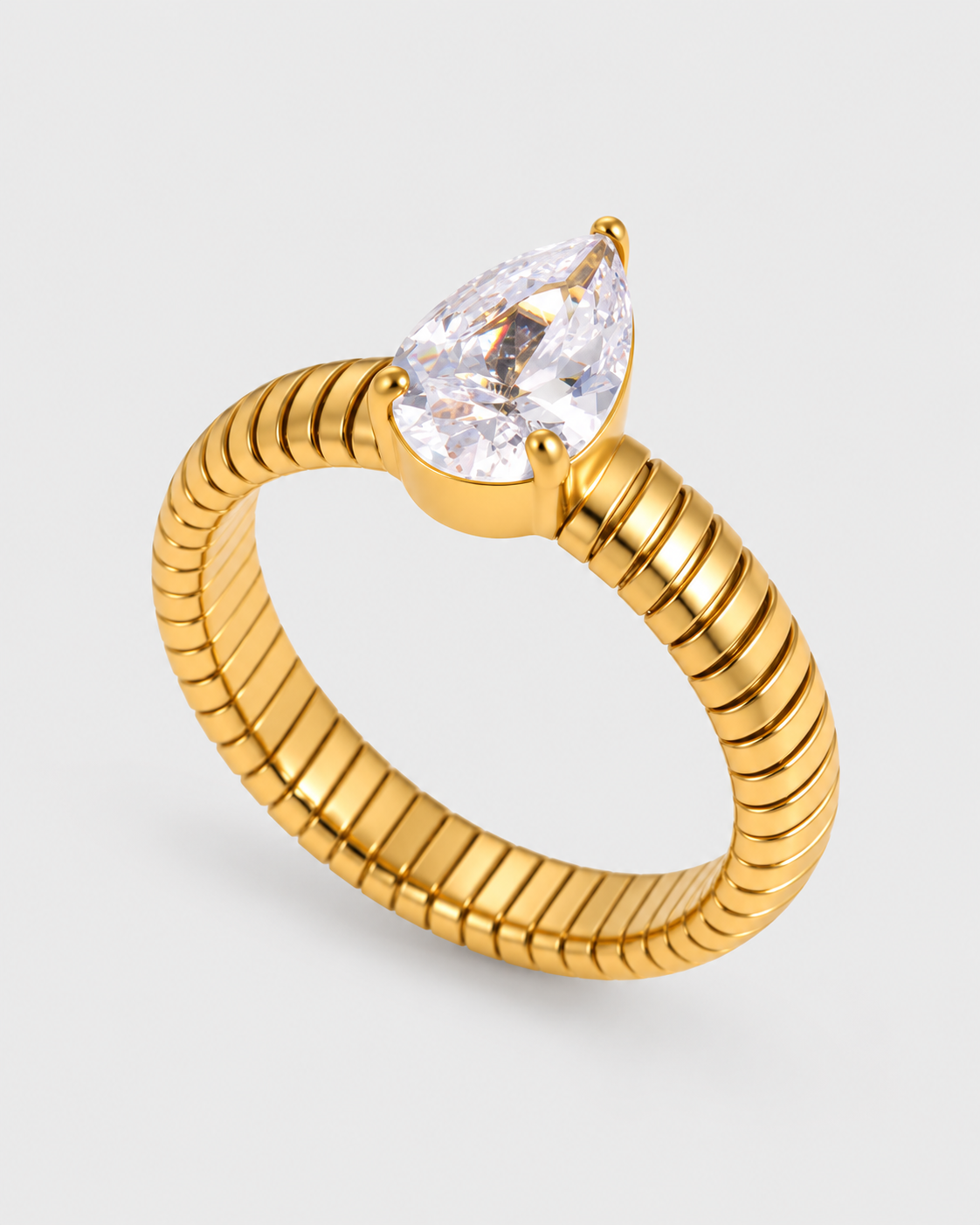 A gold ring with a textured, ribbed band and a pear-cut clear gemstone in a prong setting, shown on a light gray background.
