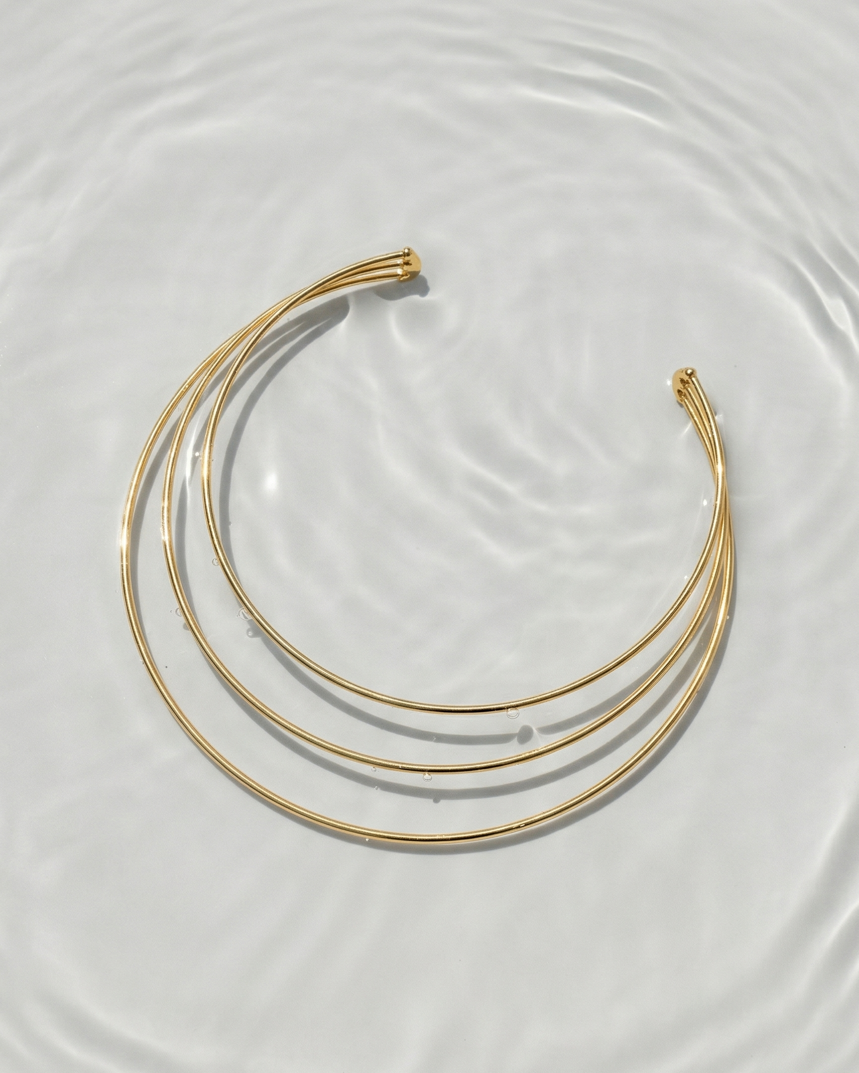 Set of gold necklaces on a textured white surface